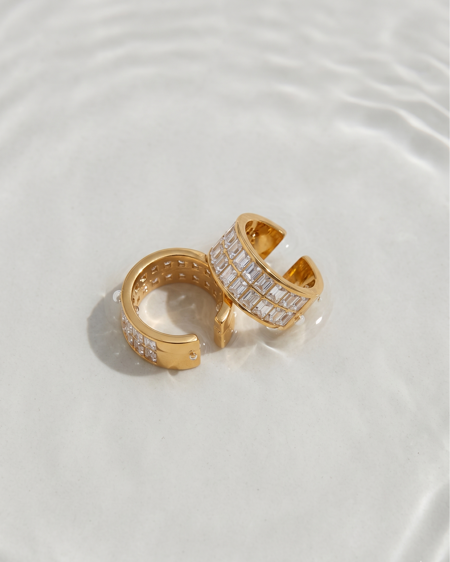 Gold hoop earrings with embedded stones on a light background