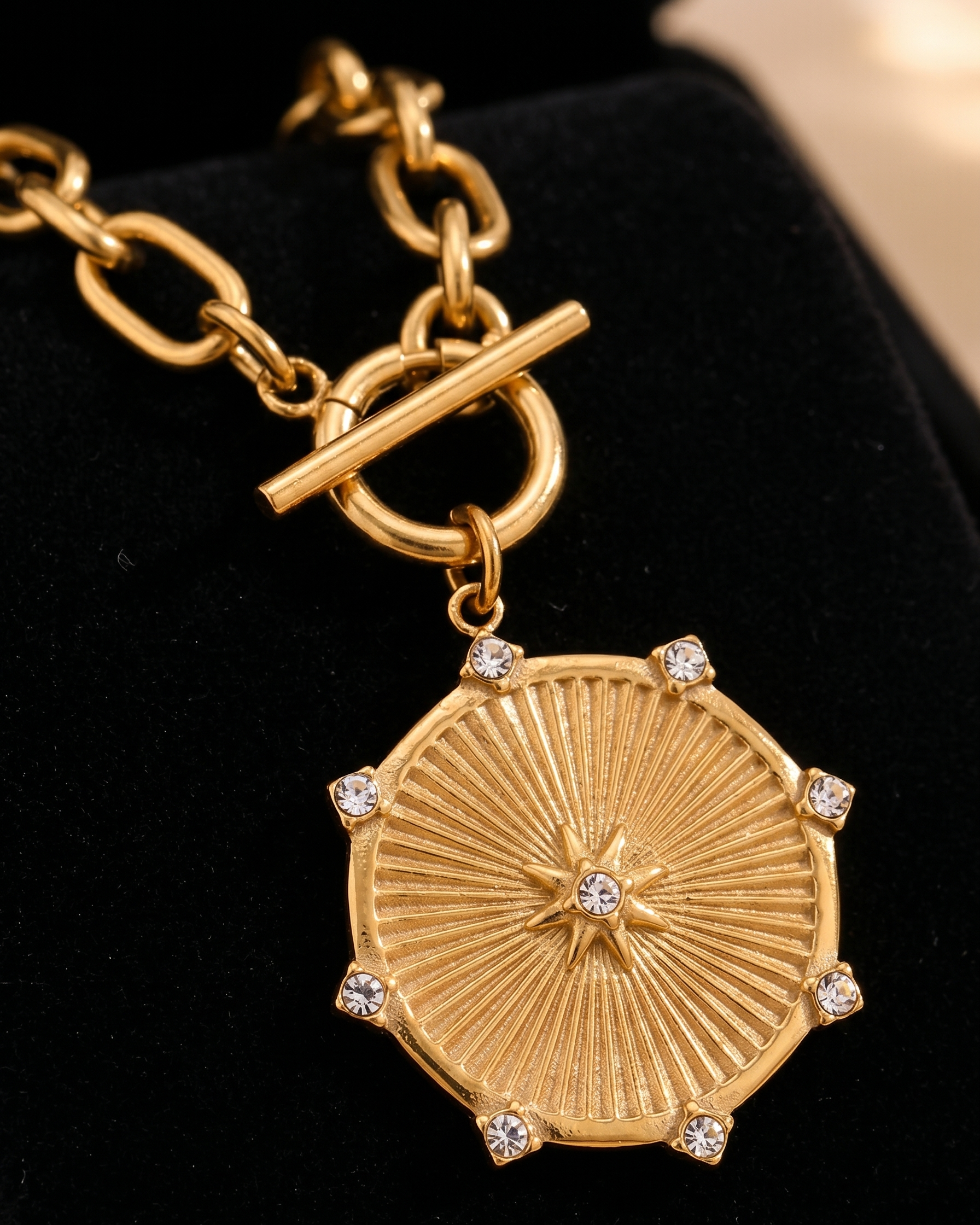 Gold necklace with a round pendant on a black background