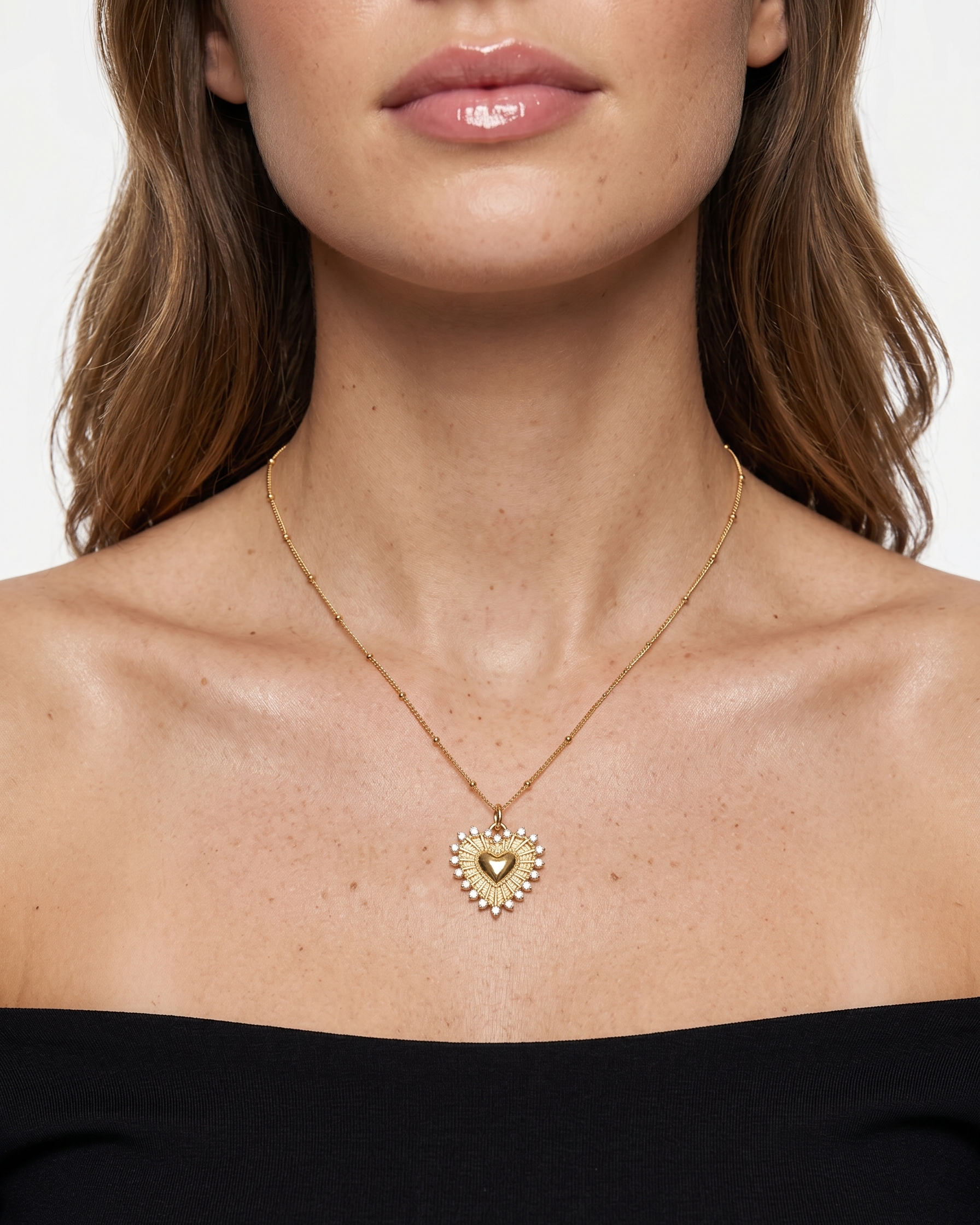 Gold heart-shaped necklace worn by a model on a plain background