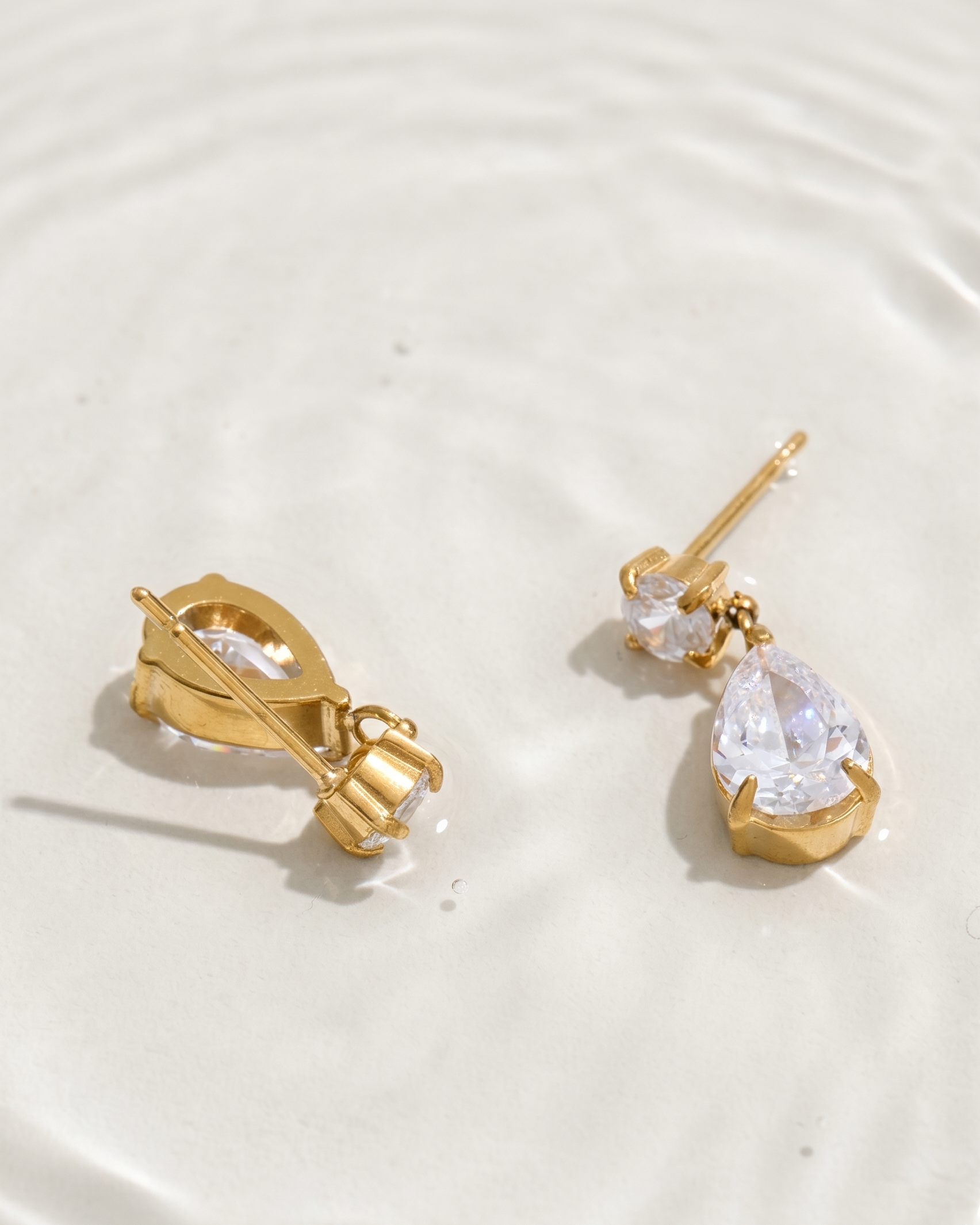 Gold earrings with clear gemstones on a white background