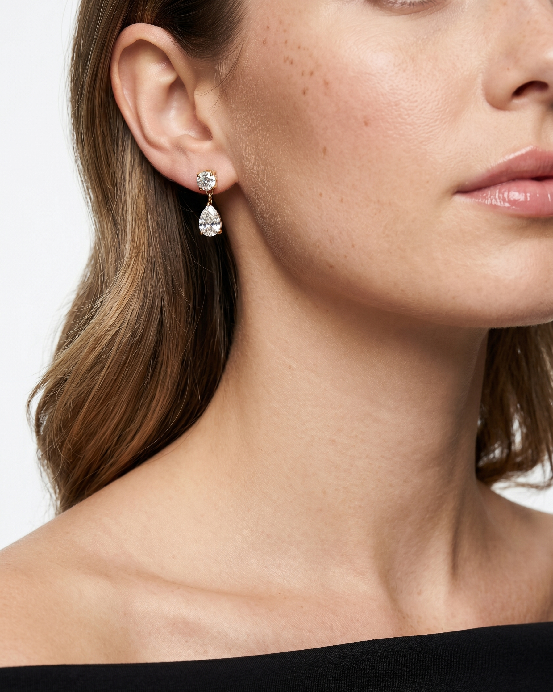 Close-up of a woman wearing pear-shaped earrings with a white background