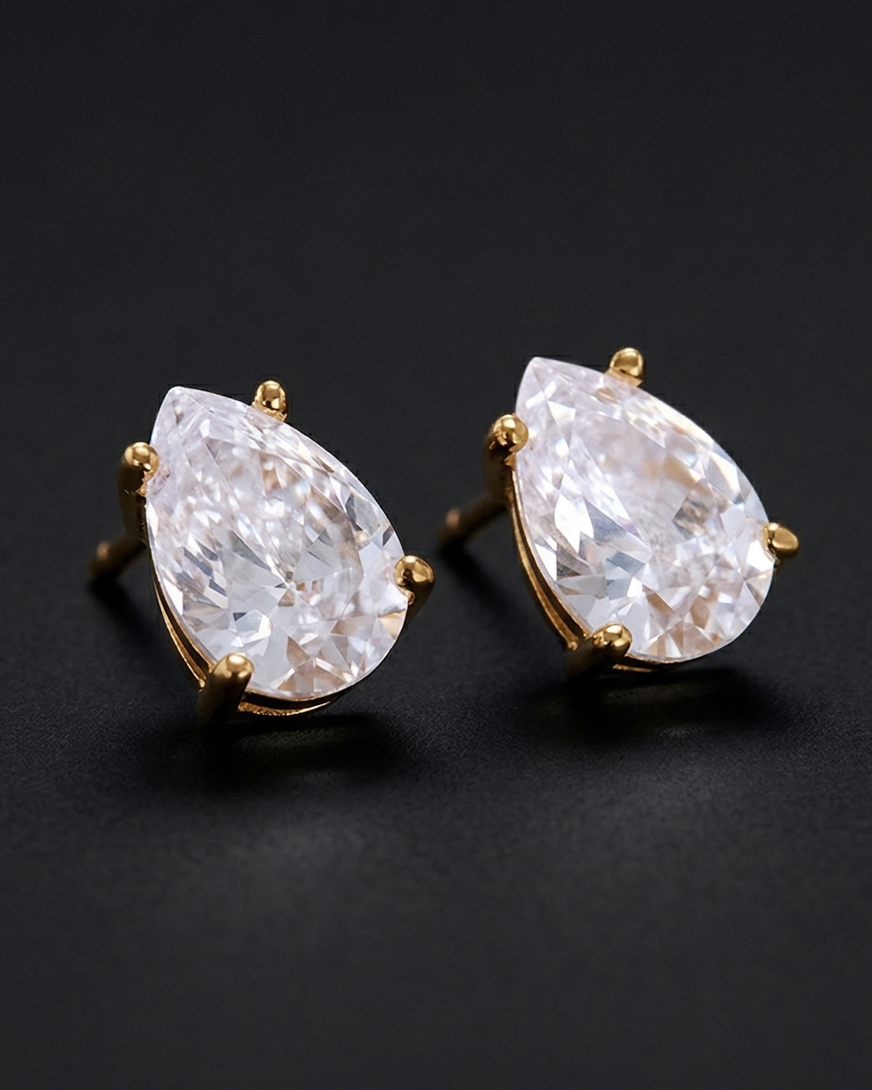 Pair of teardrop-shaped diamond earrings on a black background