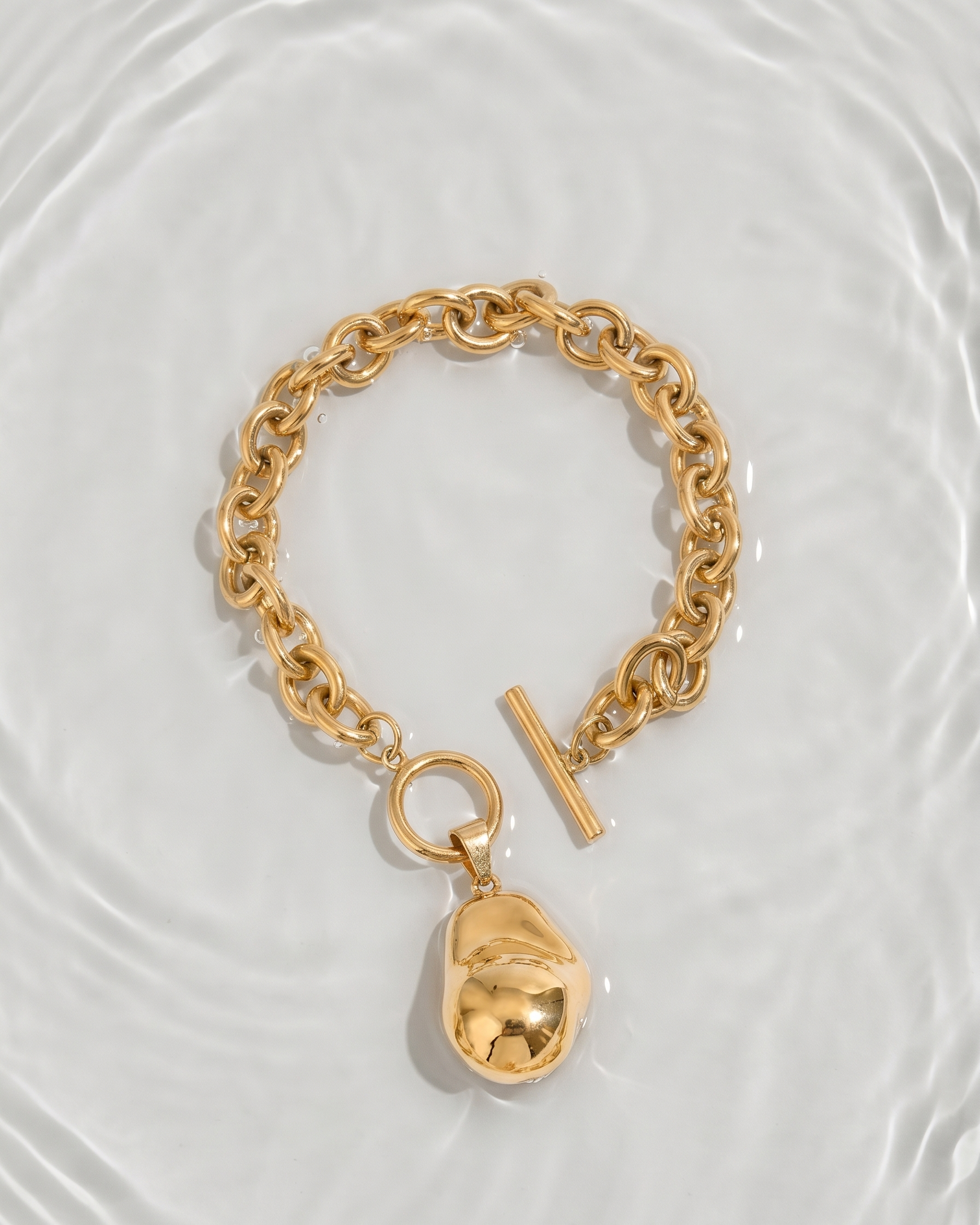 Gold chain bracelet with a lock charm on a light background