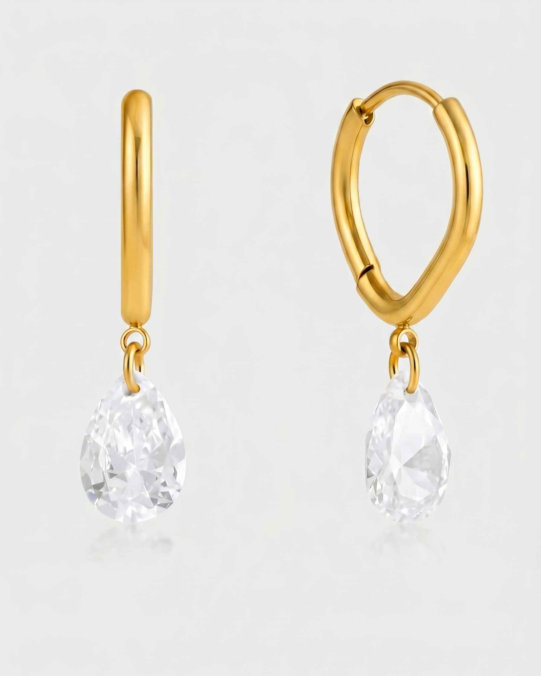 Gold hoop earrings with clear gemstones on a light gray background