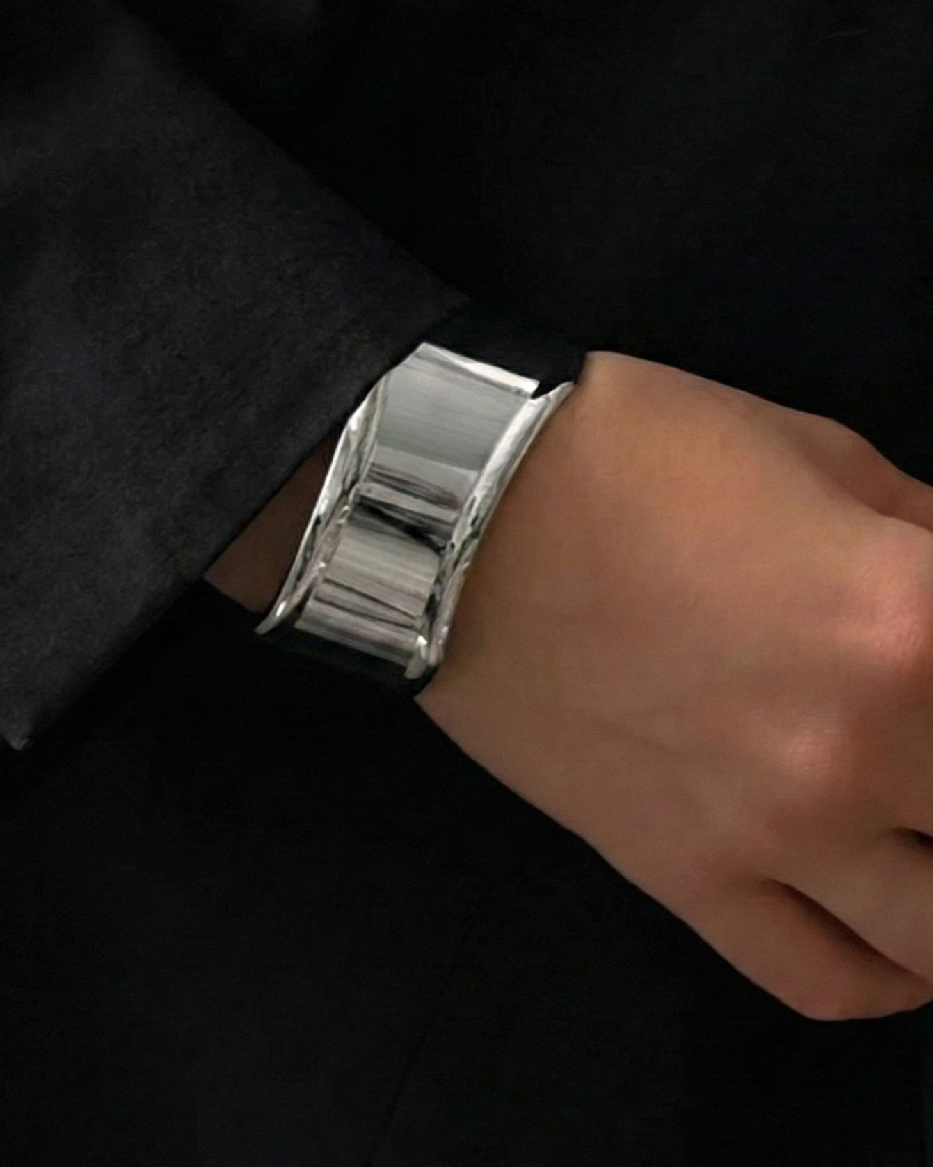 Silver bracelet on a person's wrist with a neutral background