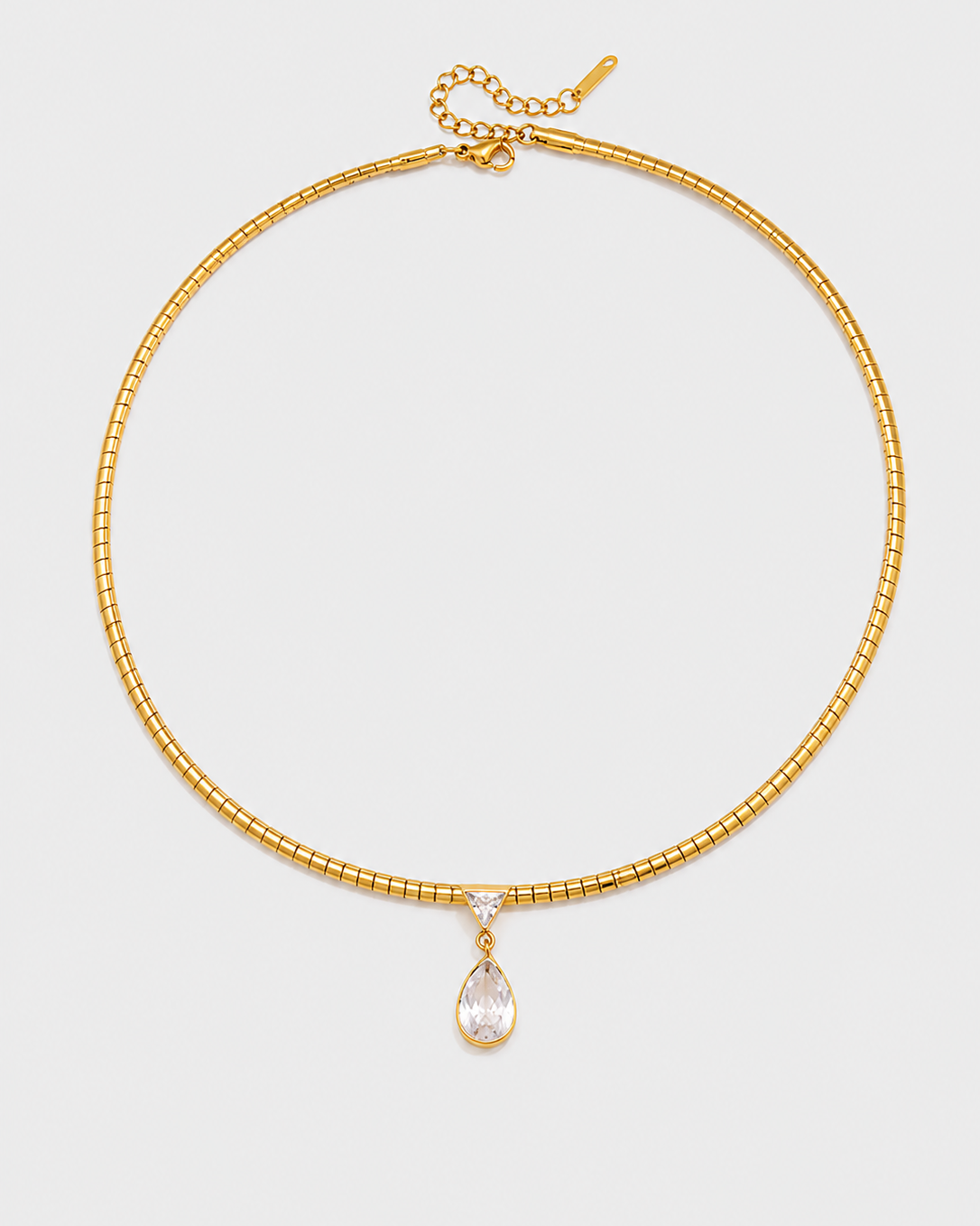 A gold-plated beaded choker necklace with a teardrop-shaped clear crystal pendant, displayed on a light gray background.