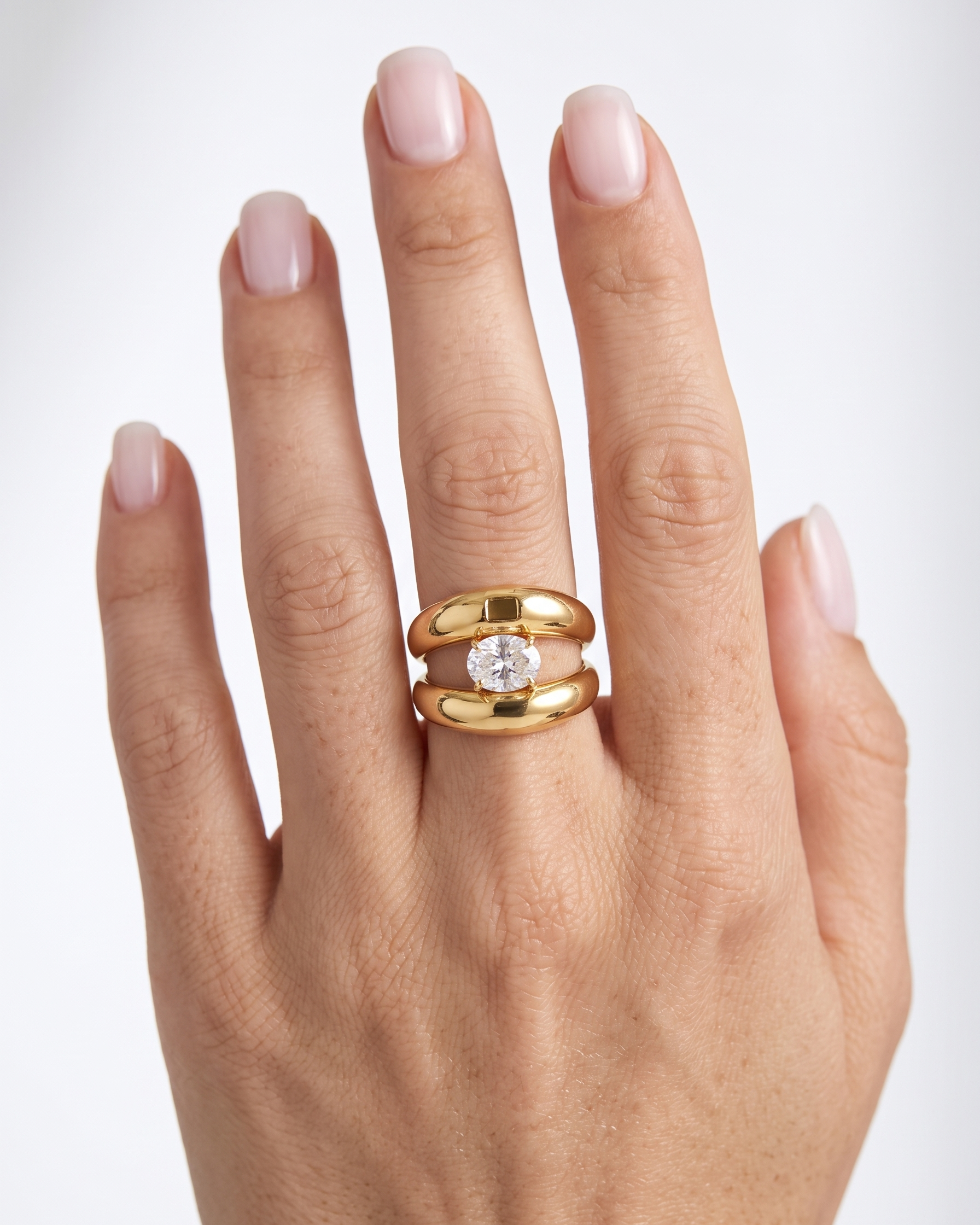 Gold ring with a diamond on a hand against a white background