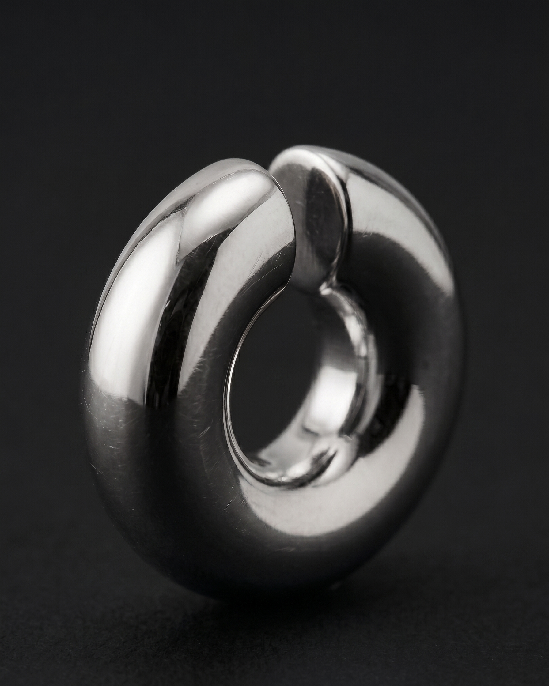 Metallic spherical object with a central circular cutout on a black background