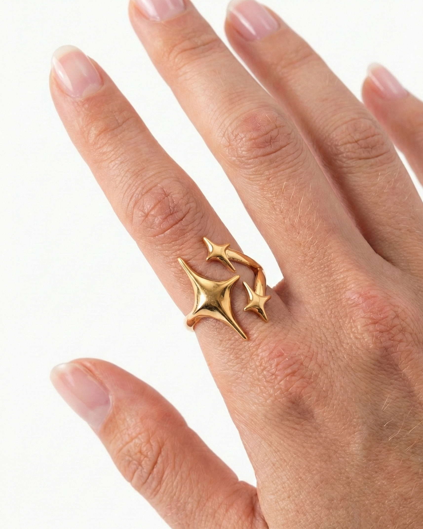 Gold ring with star design on a hand against a white background