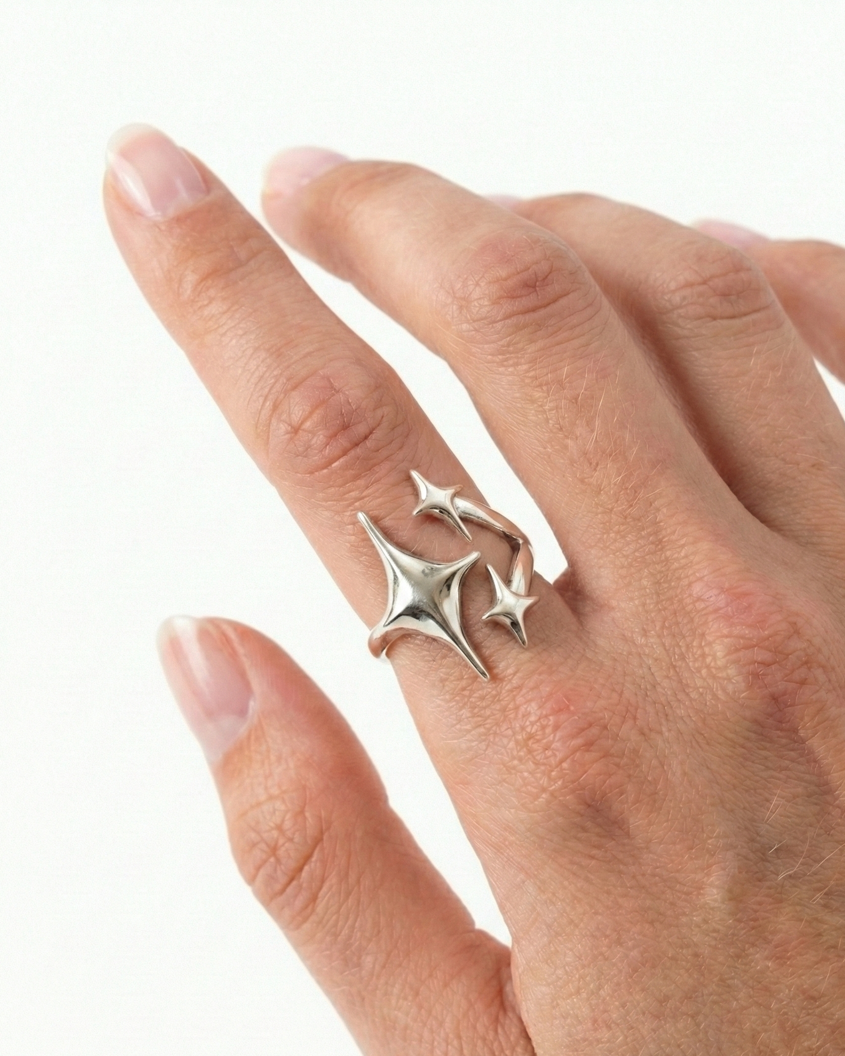 Silver star-shaped ring on a hand against a white background