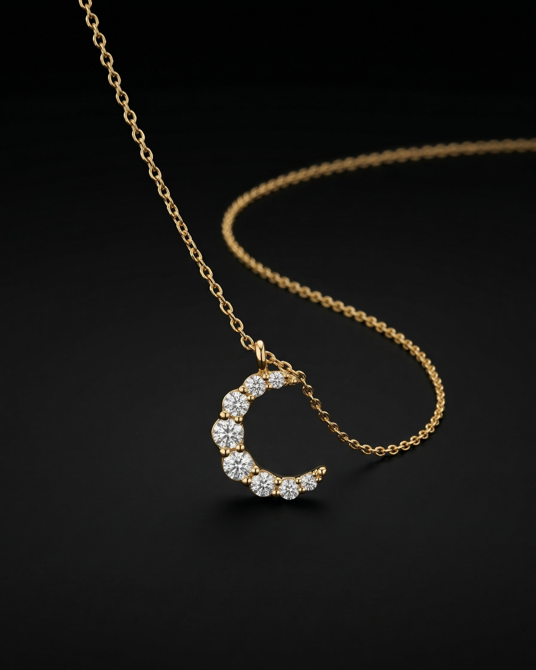 Gold necklace with a crescent moon pendant on a black background