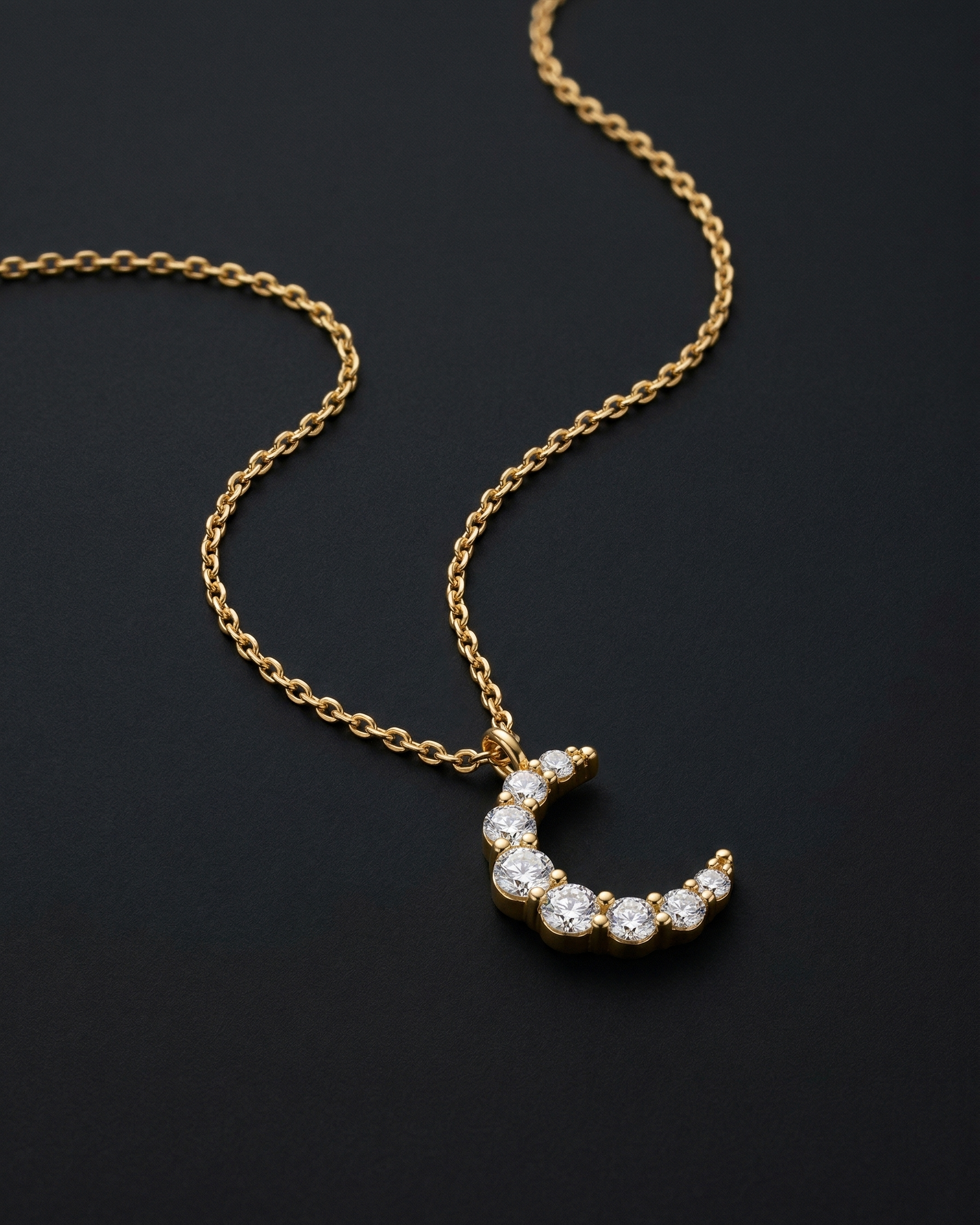 Gold necklace with a crescent moon pendant on a black background