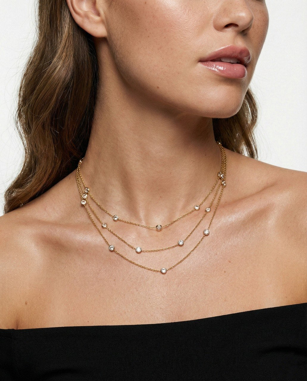 Woman wearing a gold necklace with a plain background