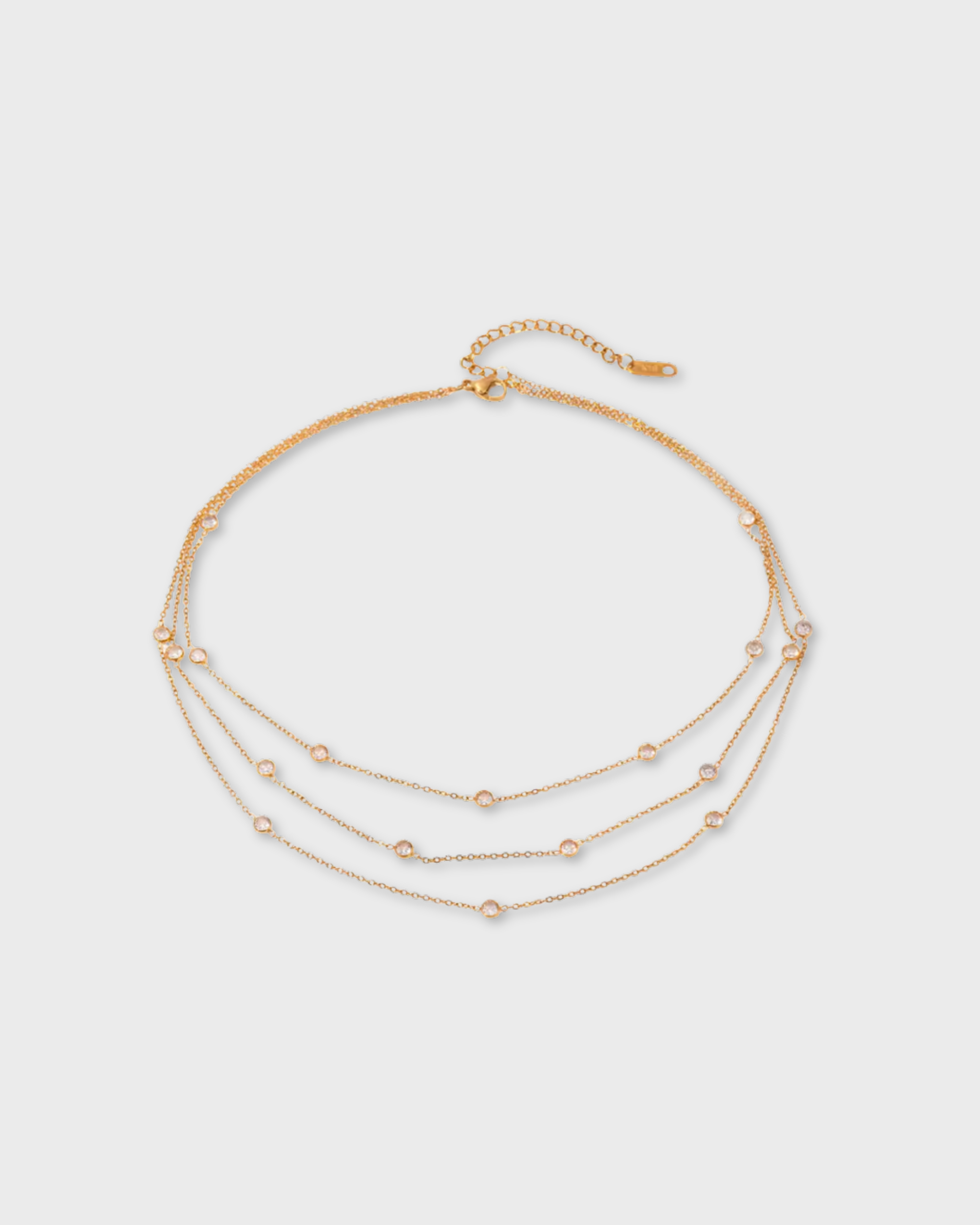 Layered gold necklaces on a light gray background