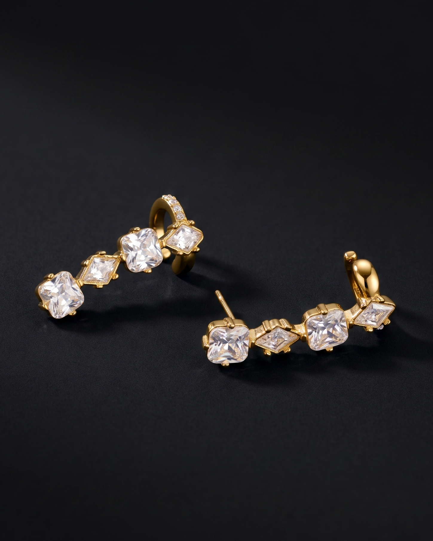 Gold earrings with clear stones on a black background