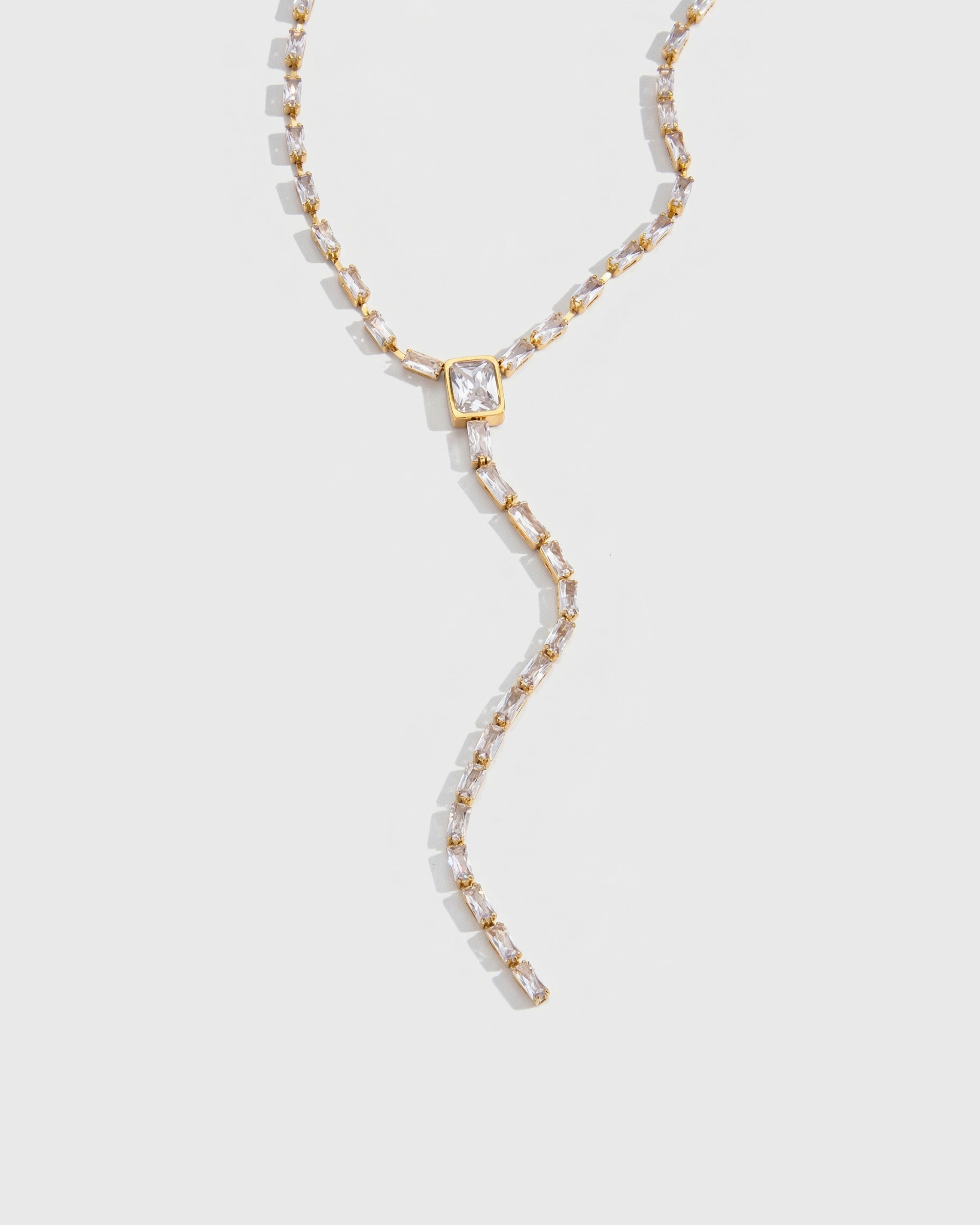 Gold necklace with a central gemstone on a light gray background