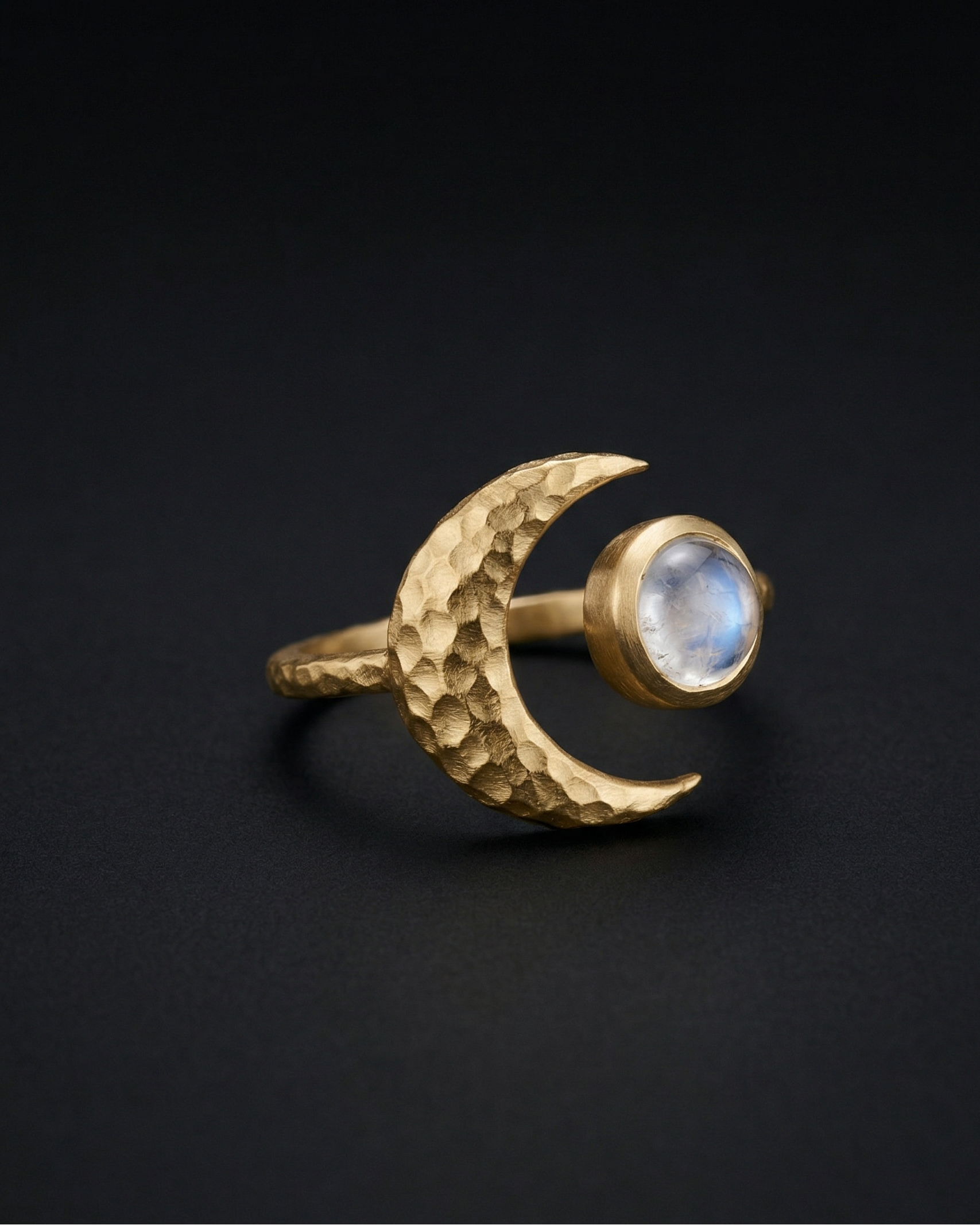 Gold ring with a moon design and gemstone on a black background