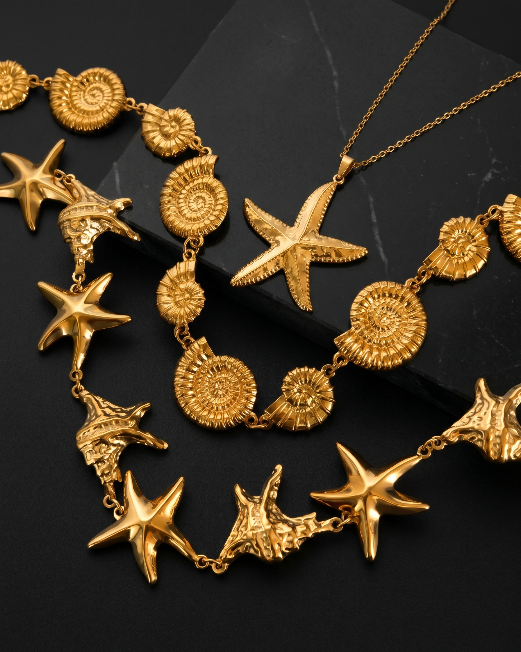 Gold necklace with starfish and ammonite designs on a black background