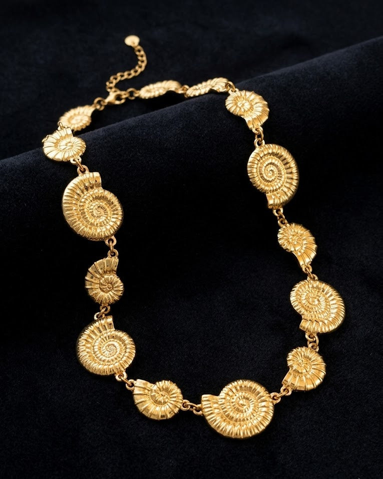 Gold necklace with intricate circular designs on a black background