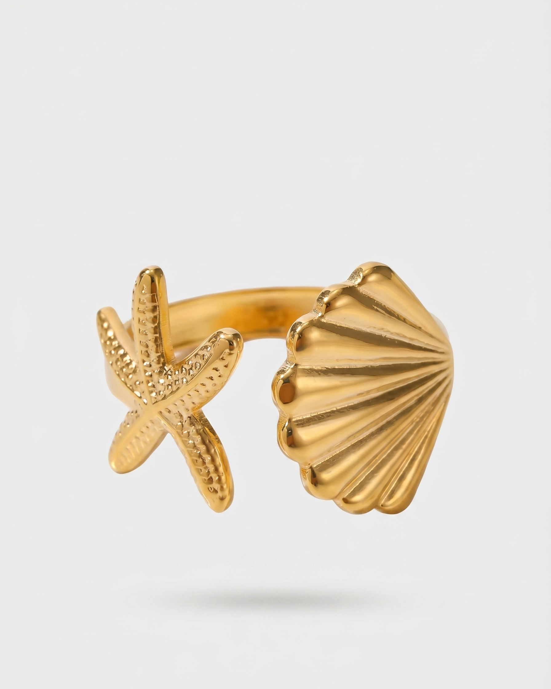 Gold ring with starfish and shell design on a light gray background