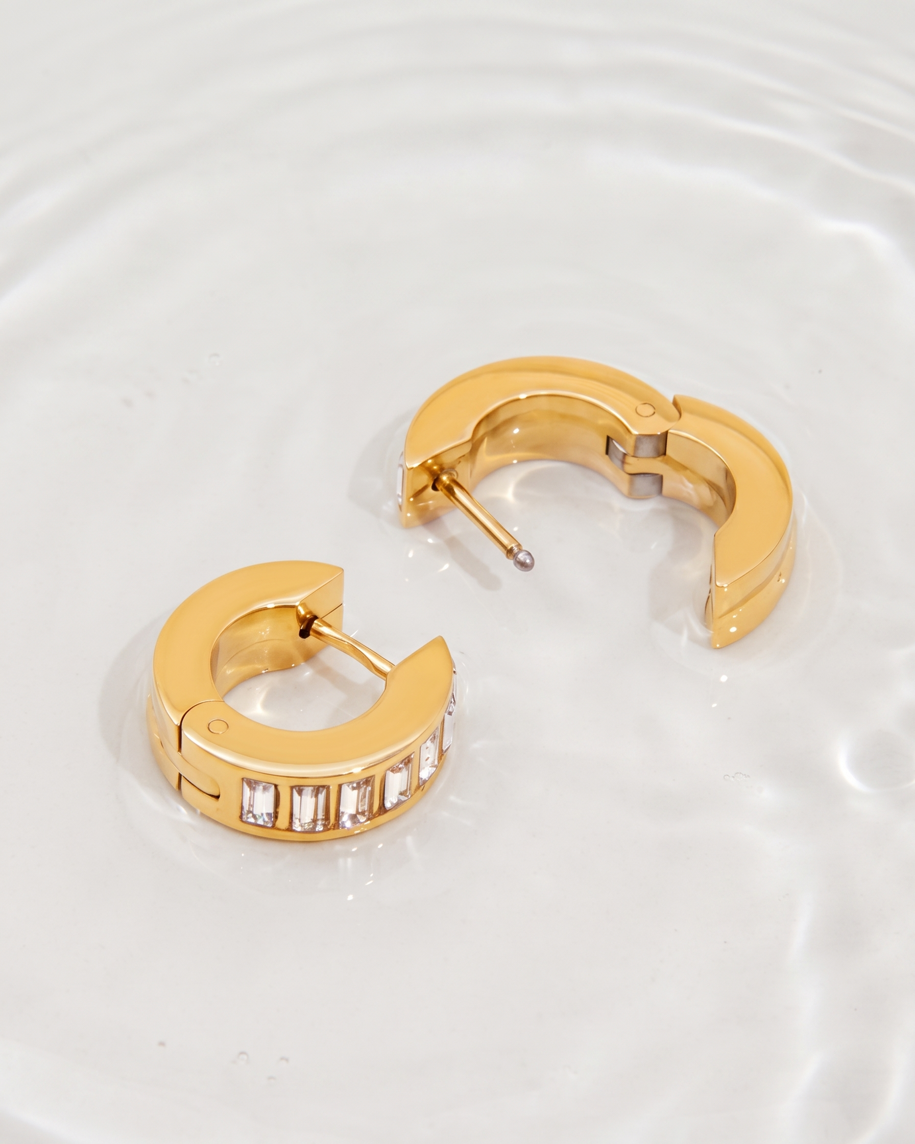 Gold hoop earrings with embedded stones on a white background