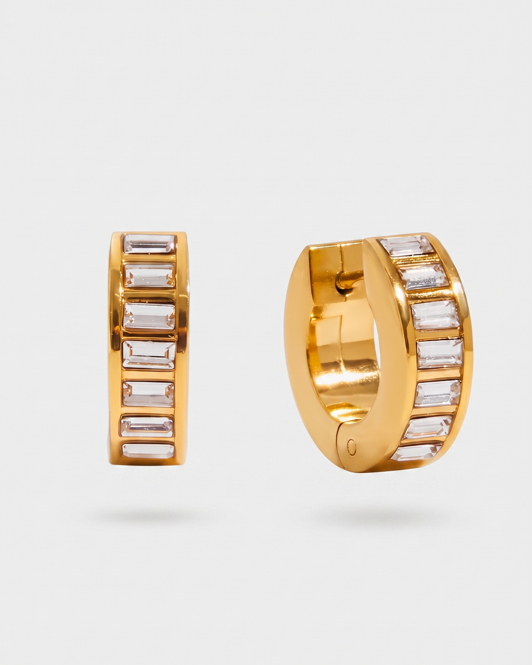 Gold hoop earrings with embedded stones on a light gray background