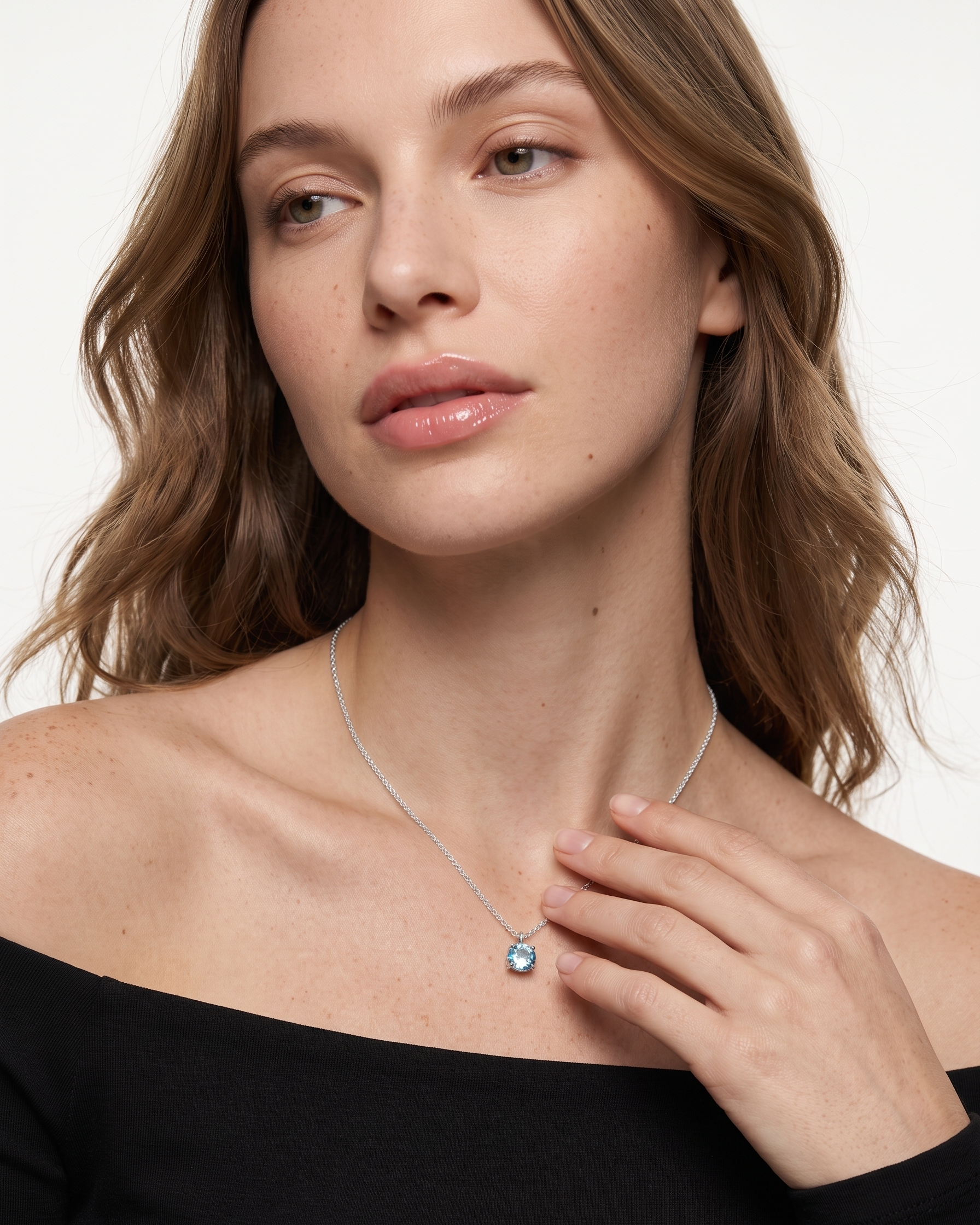 Woman wearing a silver necklace with a blue pendant on a white background