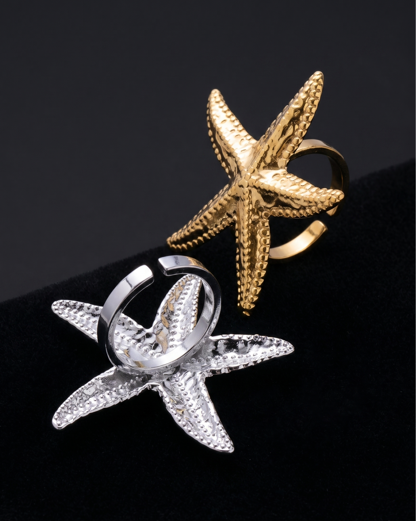 Gold and silver starfish-shaped rings on a black background