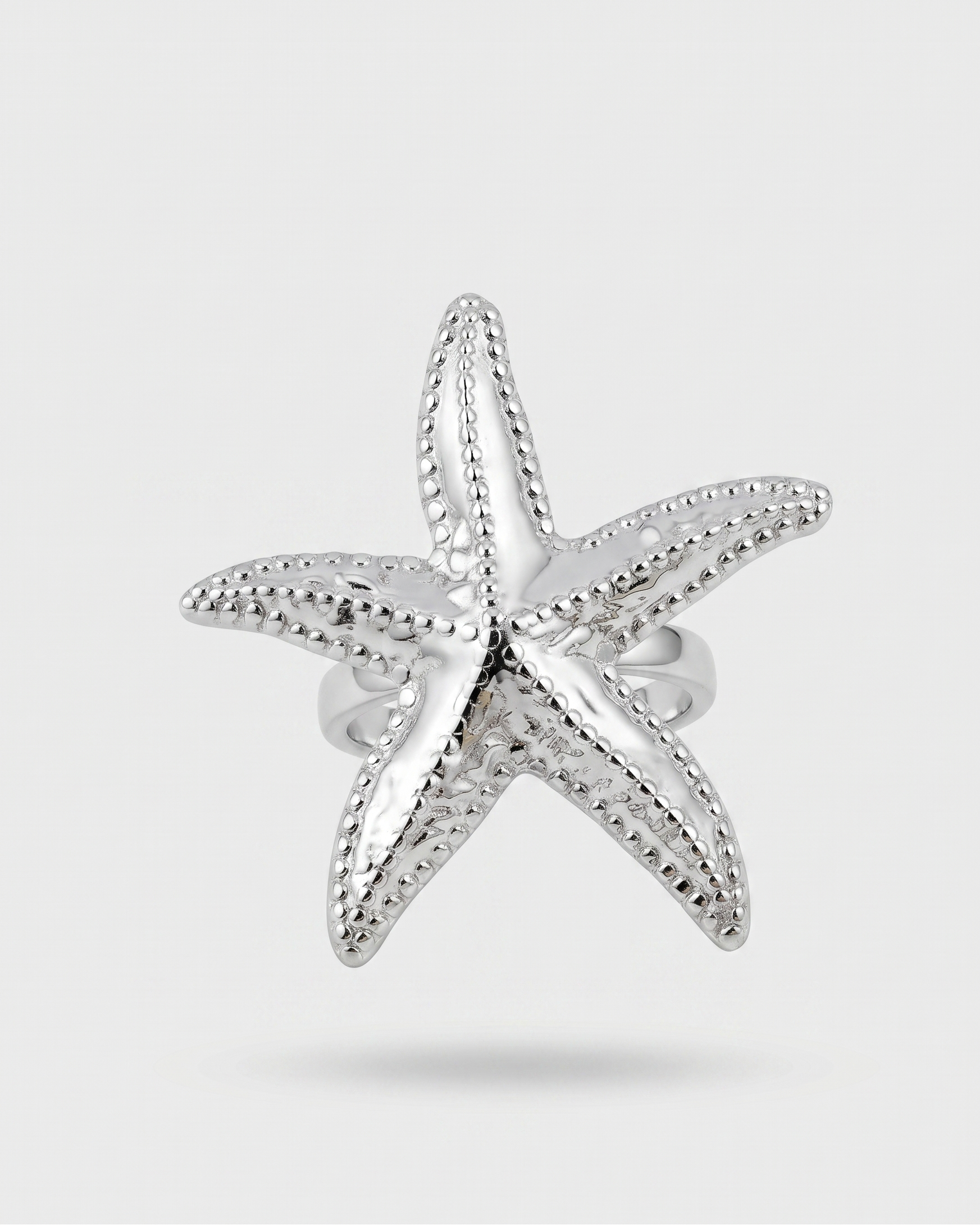 Silver starfish-shaped earring on a light gray background