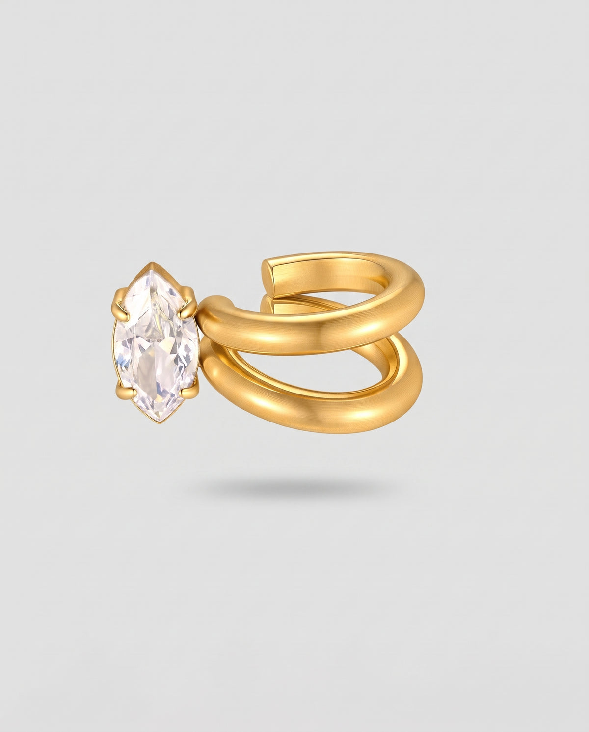 A gold ring with a double-band wrap design and a marquise-cut clear gemstone, shown on a light gray background.