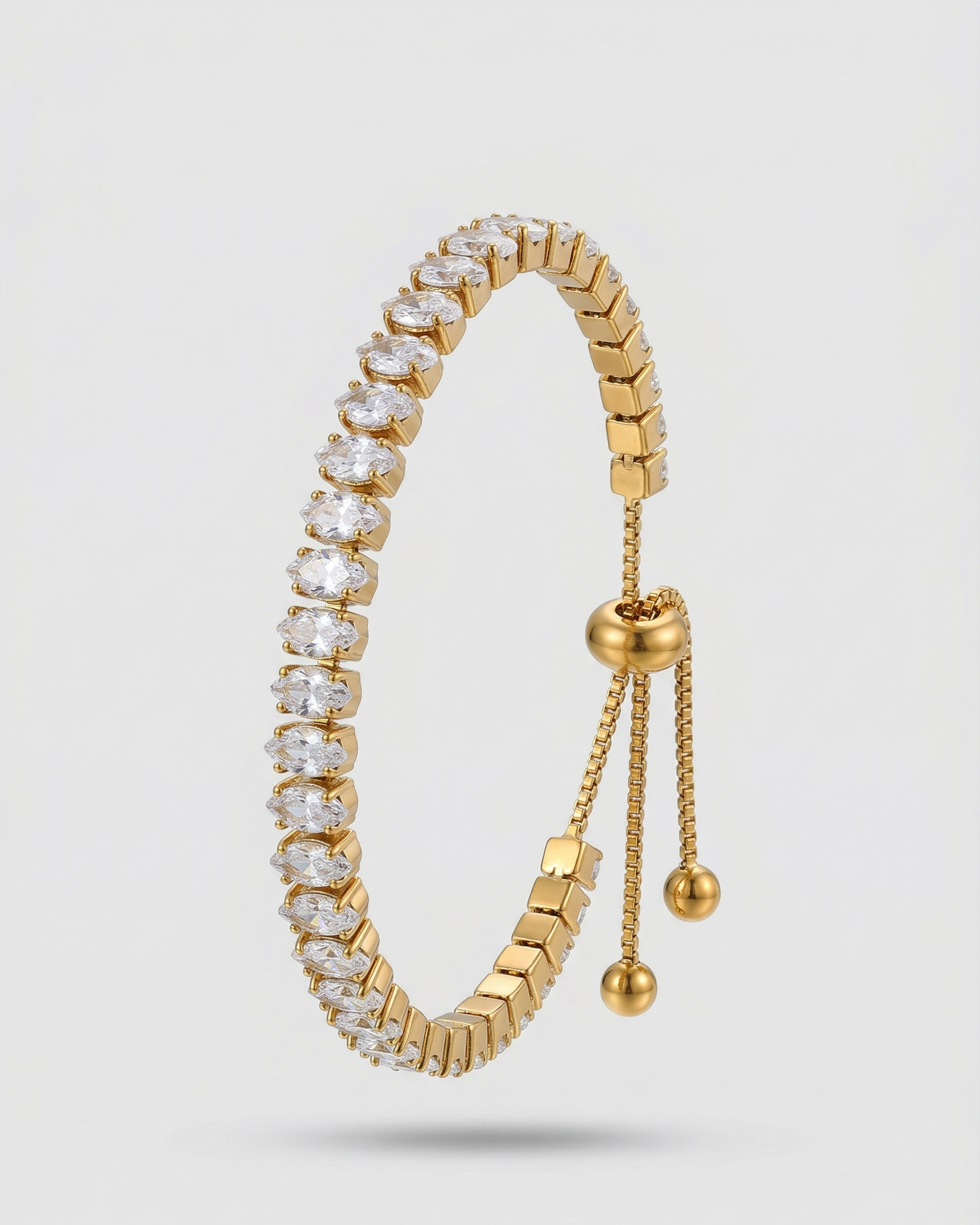 Gold bracelet with clear gemstones on a light gray background
