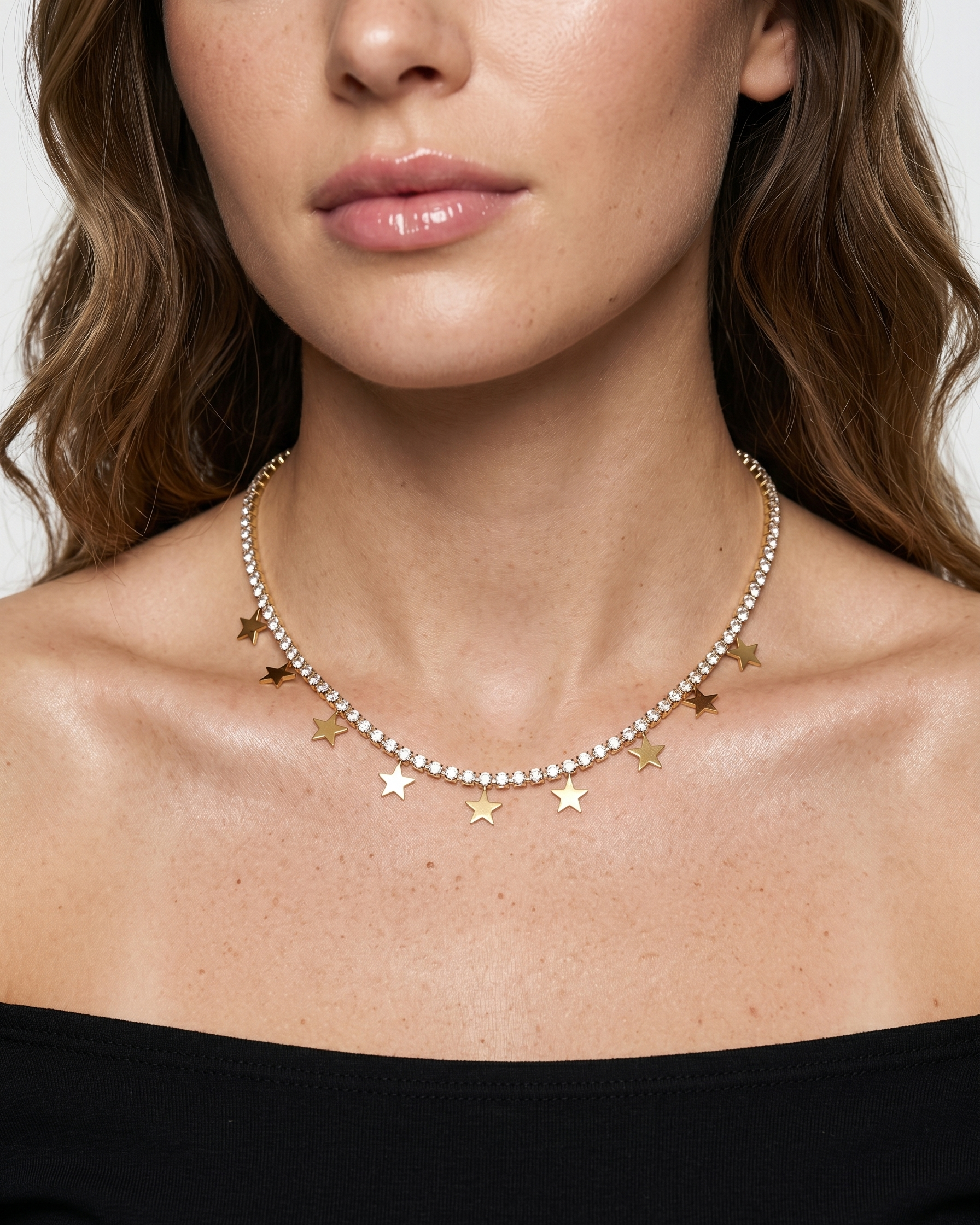 Close-up of a woman wearing a delicate necklace with star-shaped pendants on a neutral background
