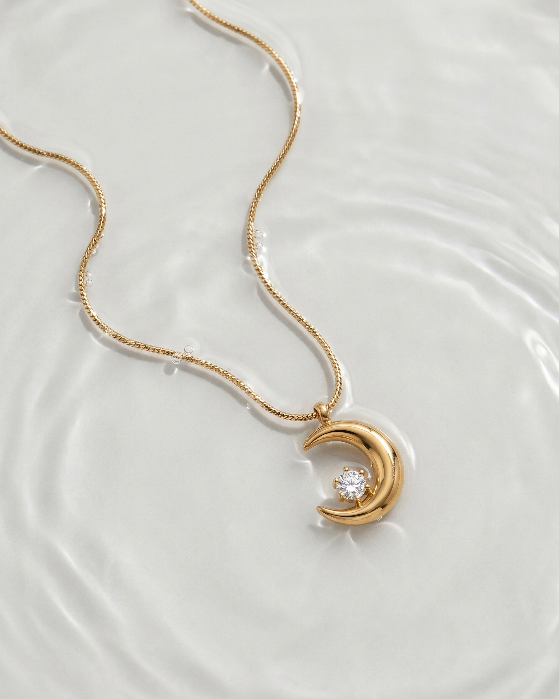 Gold necklace with a crescent moon pendant on a white background