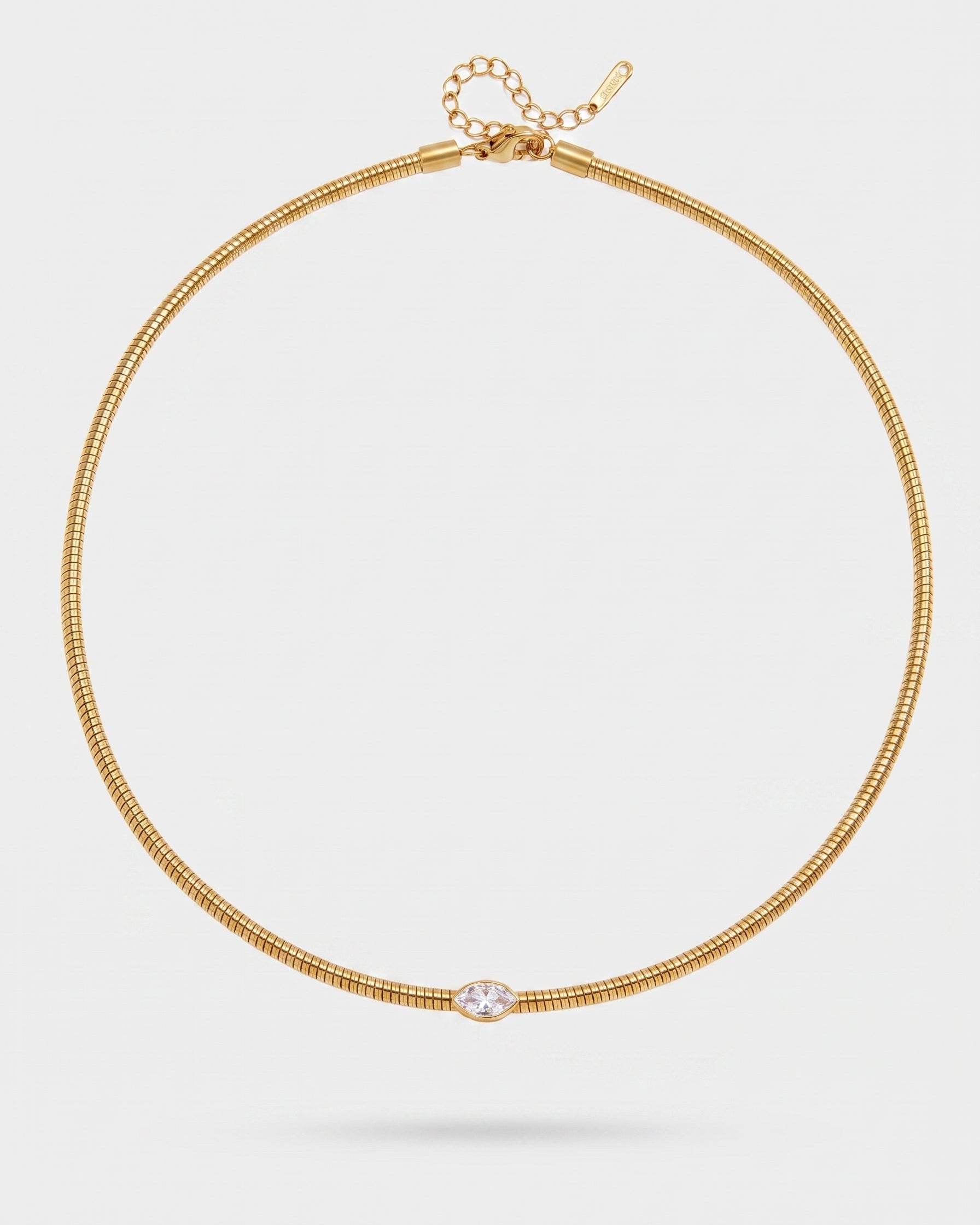A delicate gold snake chain choker necklace with a small marquise-cut clear gemstone at the center, displayed on a light gray background.