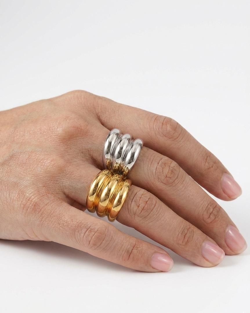 Hand wearing two gold rings on a white background