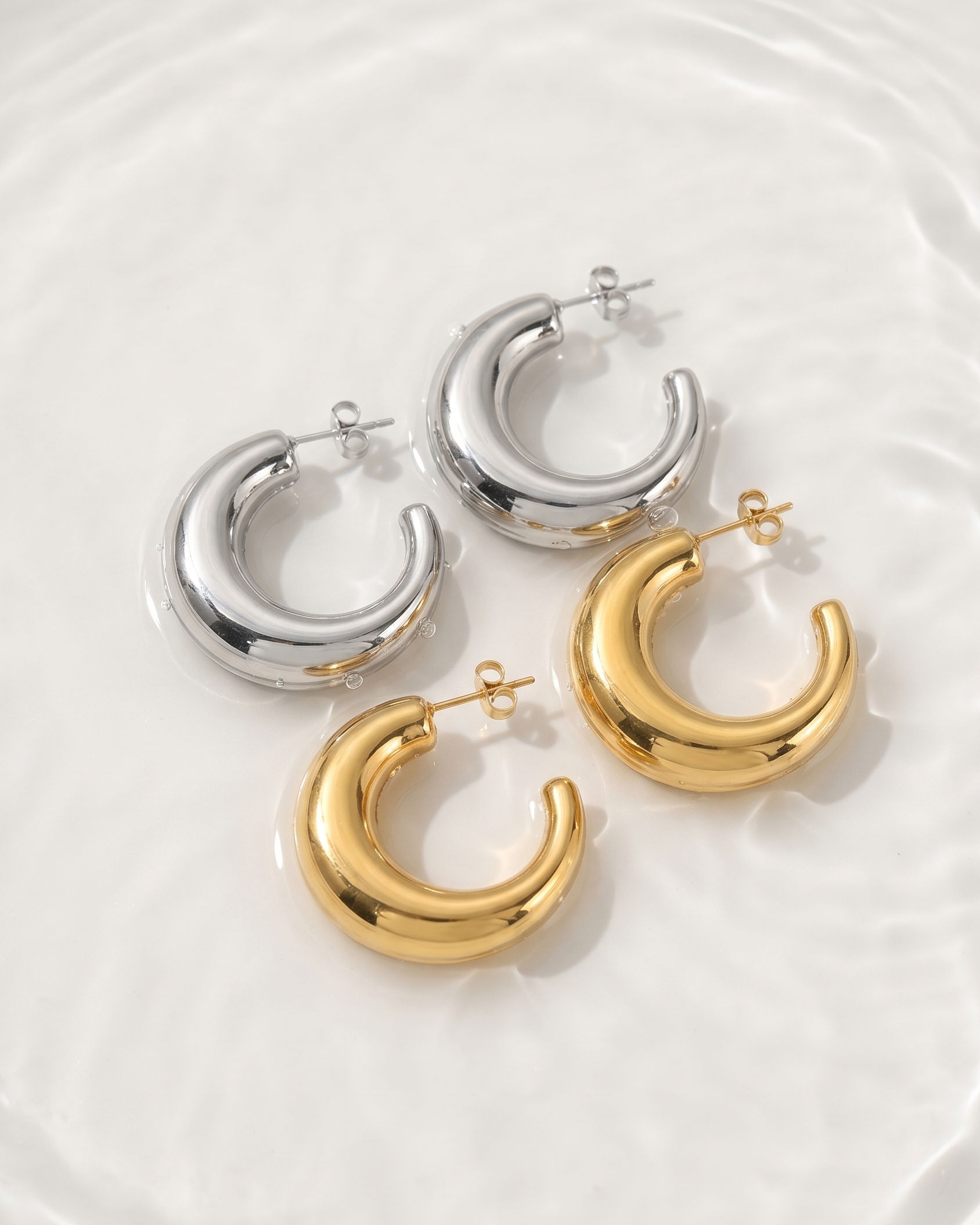 Pair of gold and silver hoop earrings on a white background