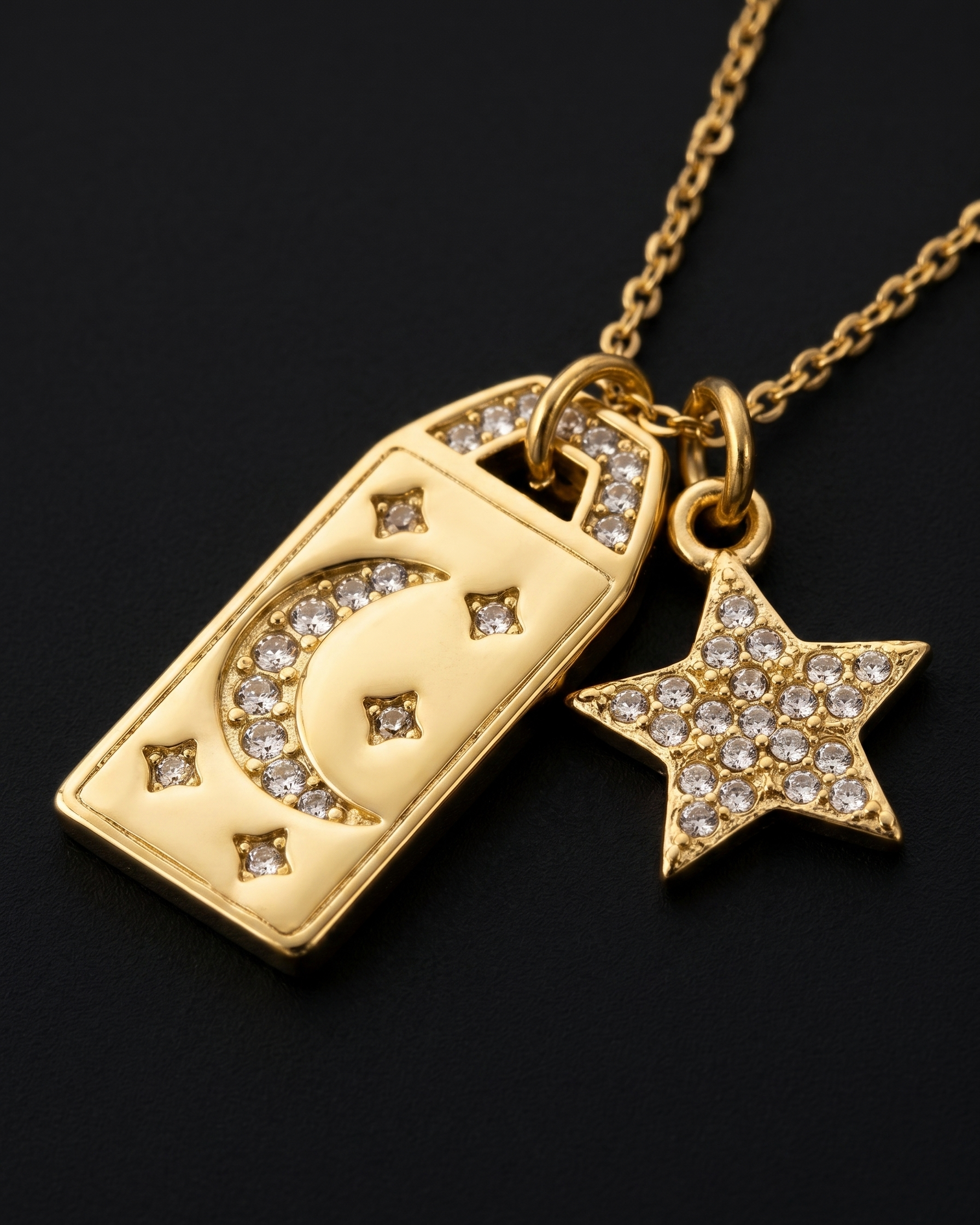 Gold necklace with a rectangular pendant and star-shaped charm on a black background