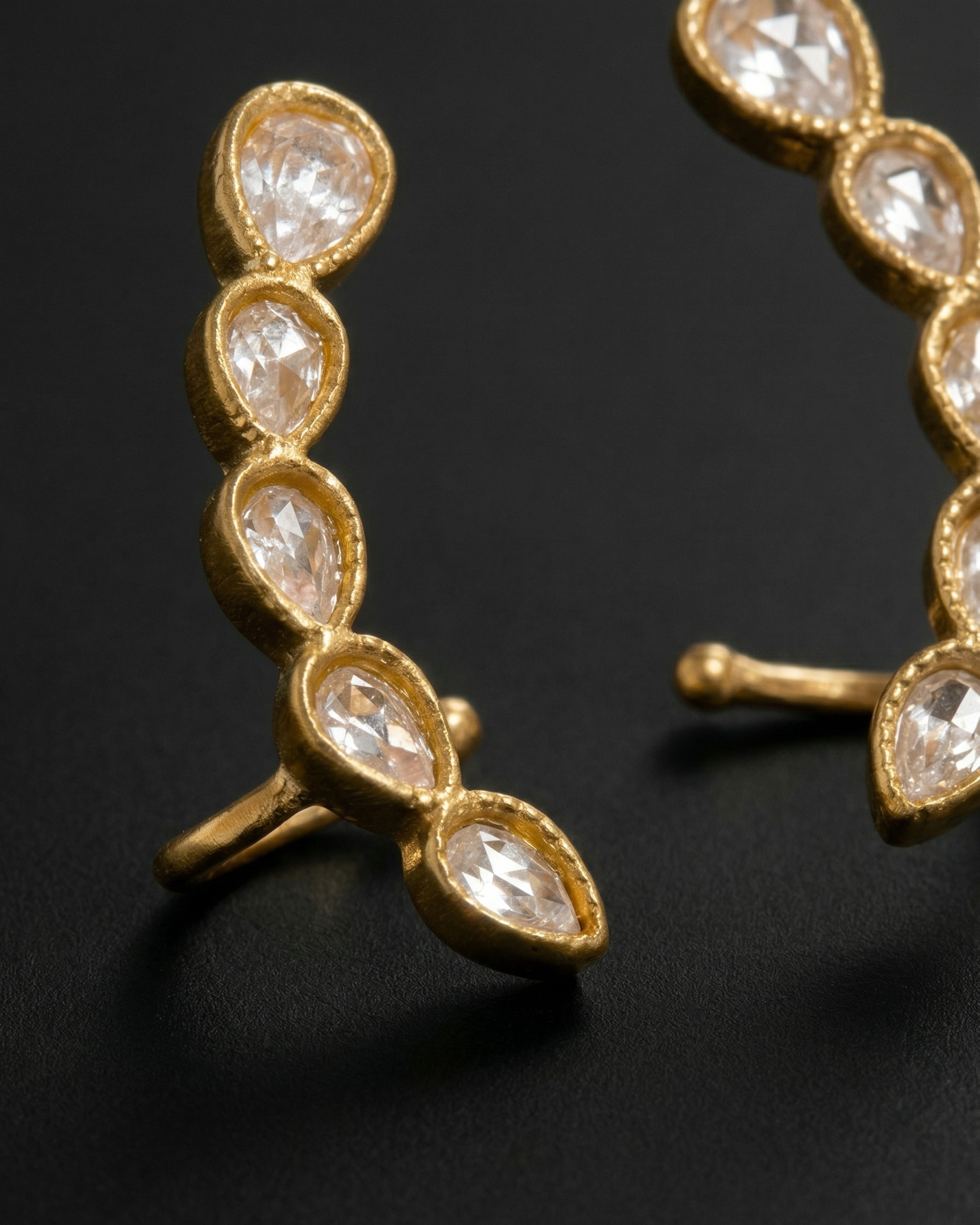 Gold hoop earrings with clear gemstones on a dark background