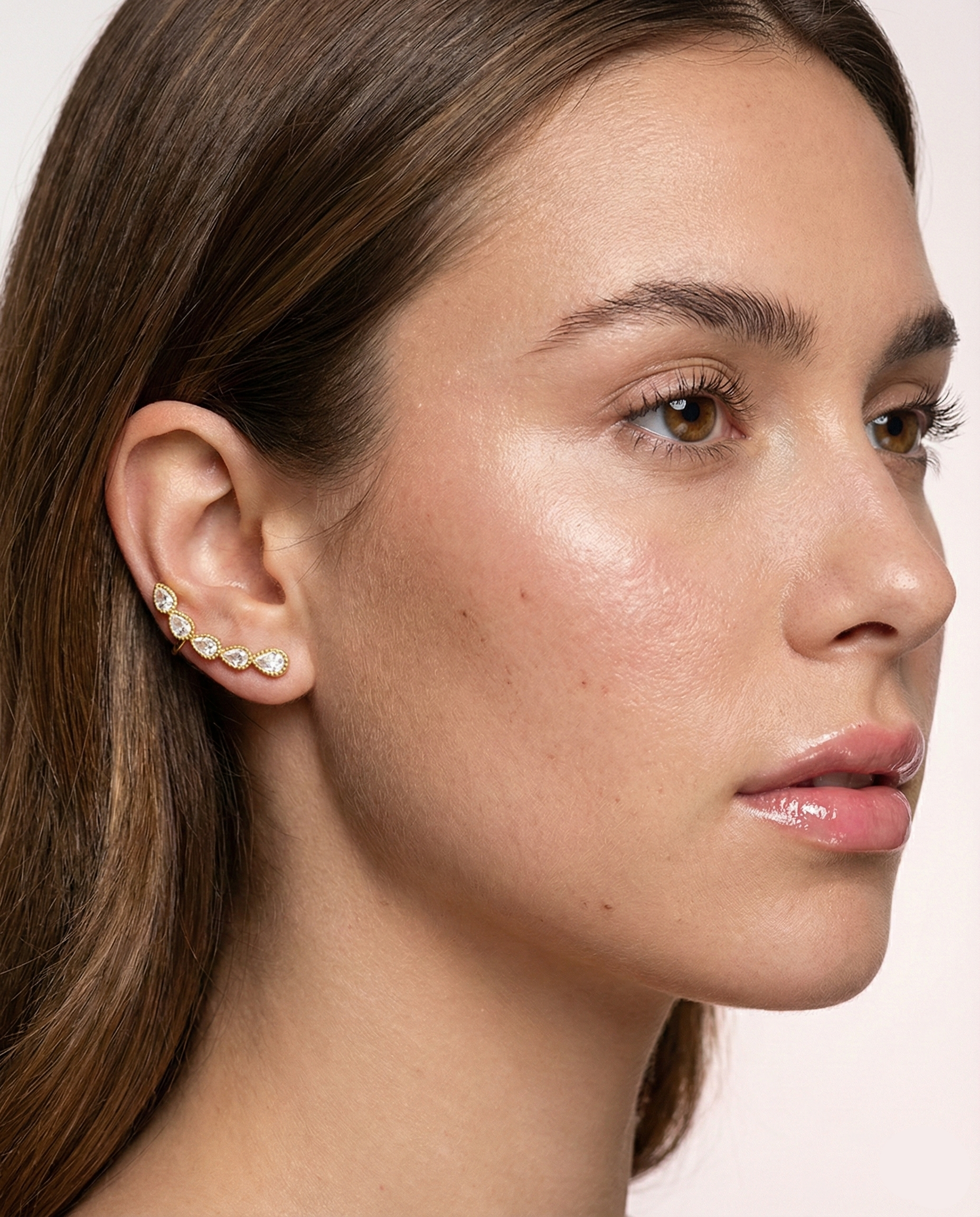 Close-up of a woman wearing diamond earrings on a light background