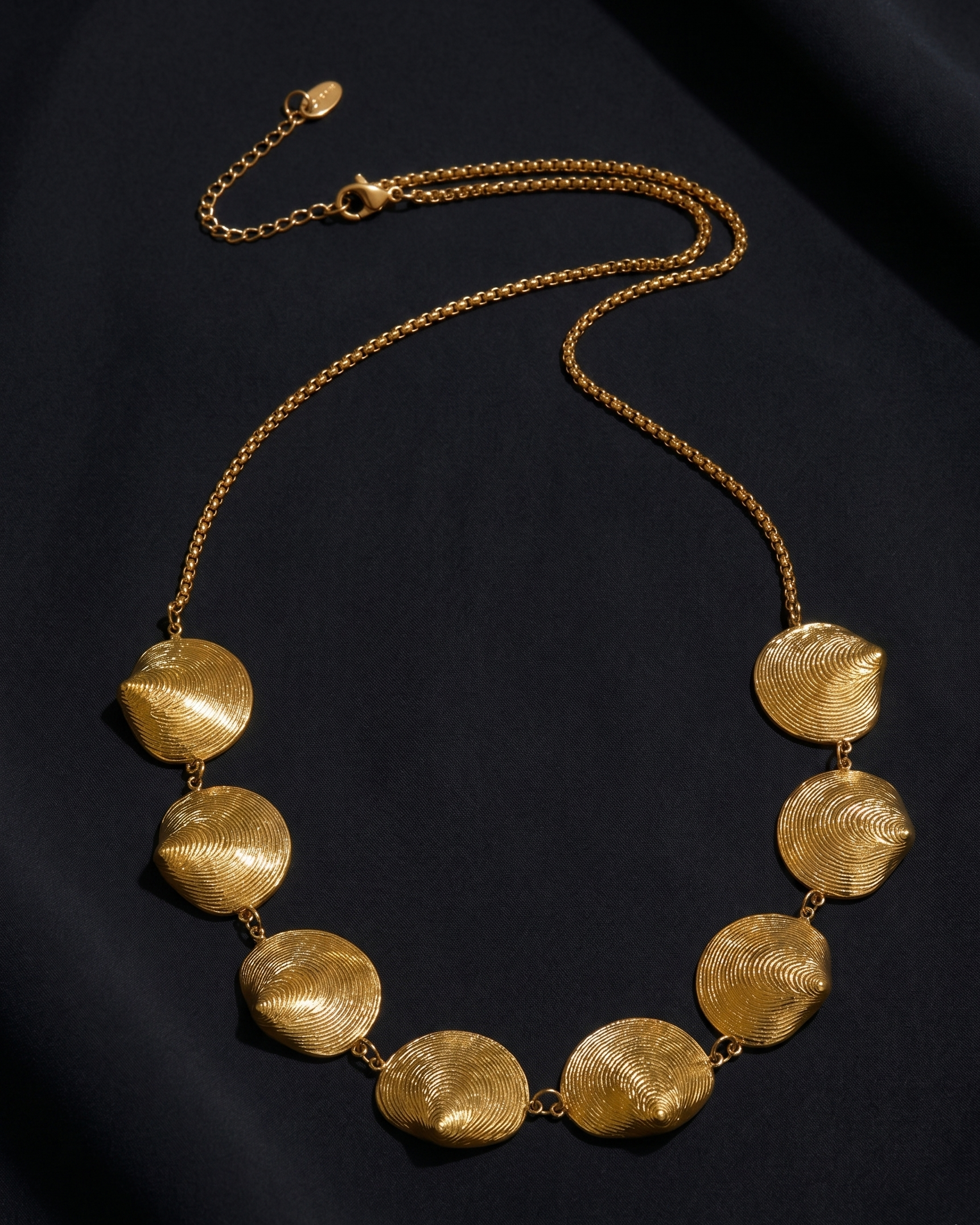 Gold necklace with textured discs on a black background