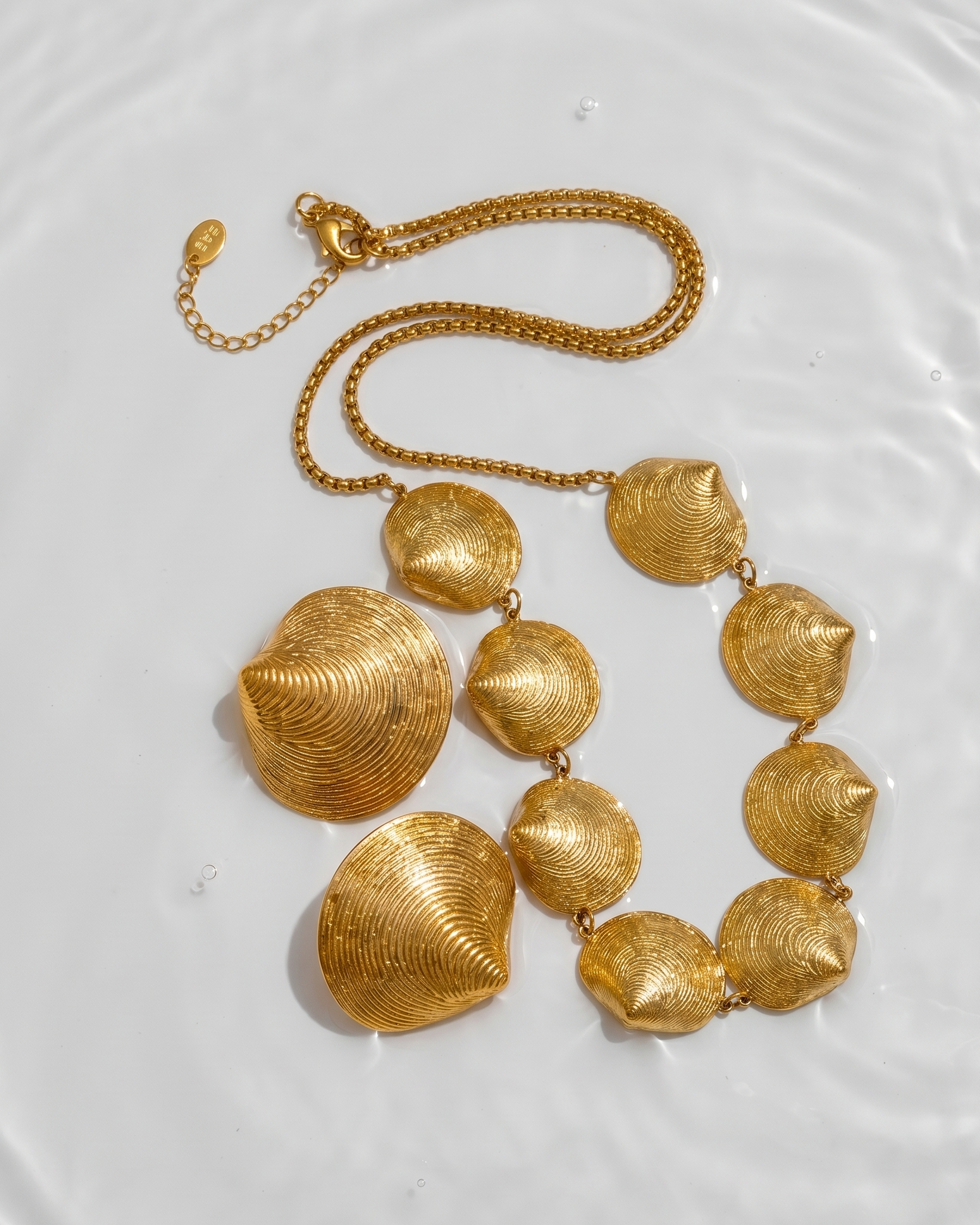 Gold necklace with shell-like designs on a white background