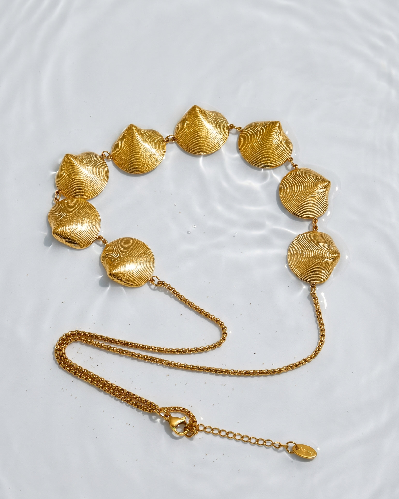 Gold necklace with leaf-like beads on a light gray background
