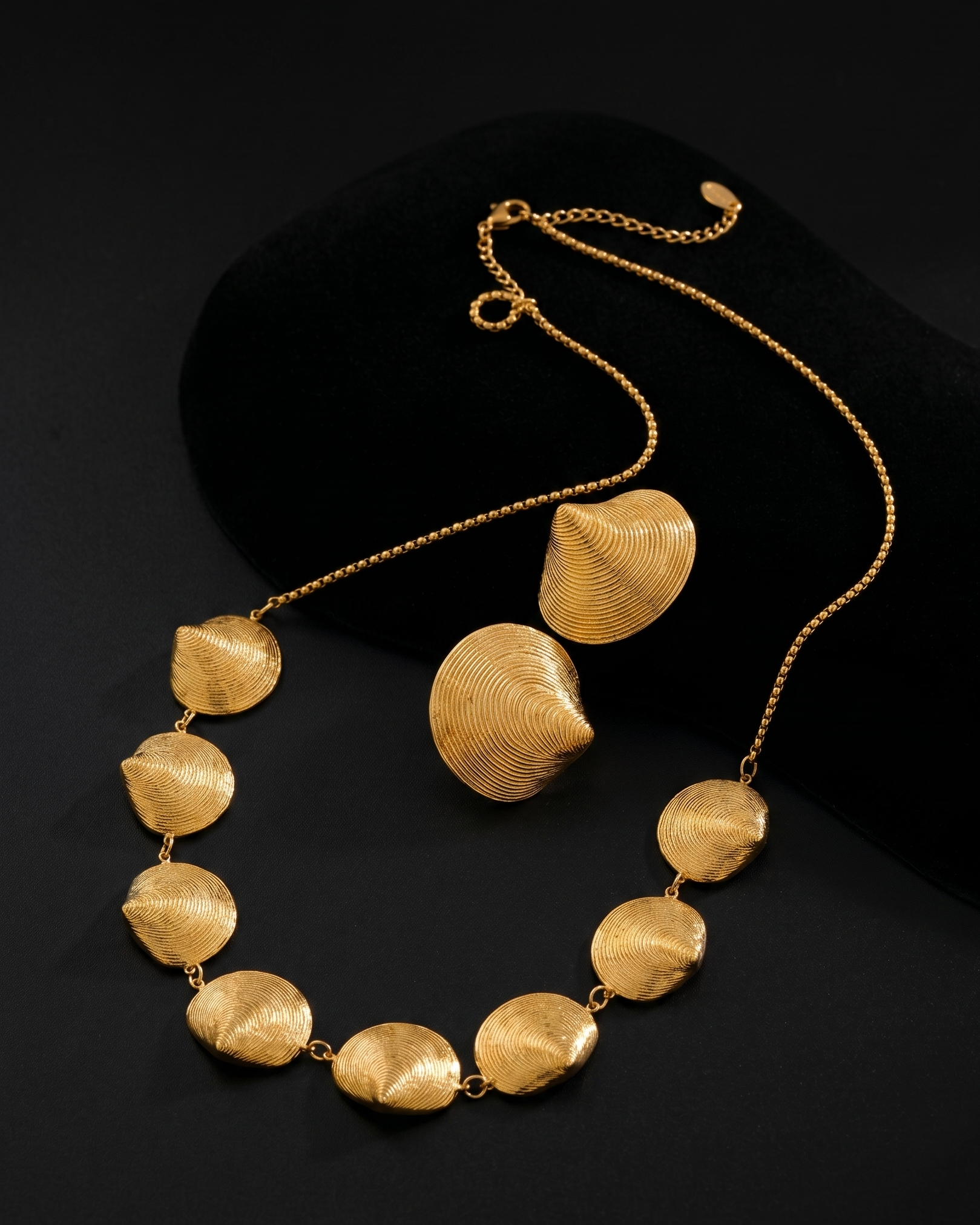 Gold necklace with leaf-shaped pendants on a black background