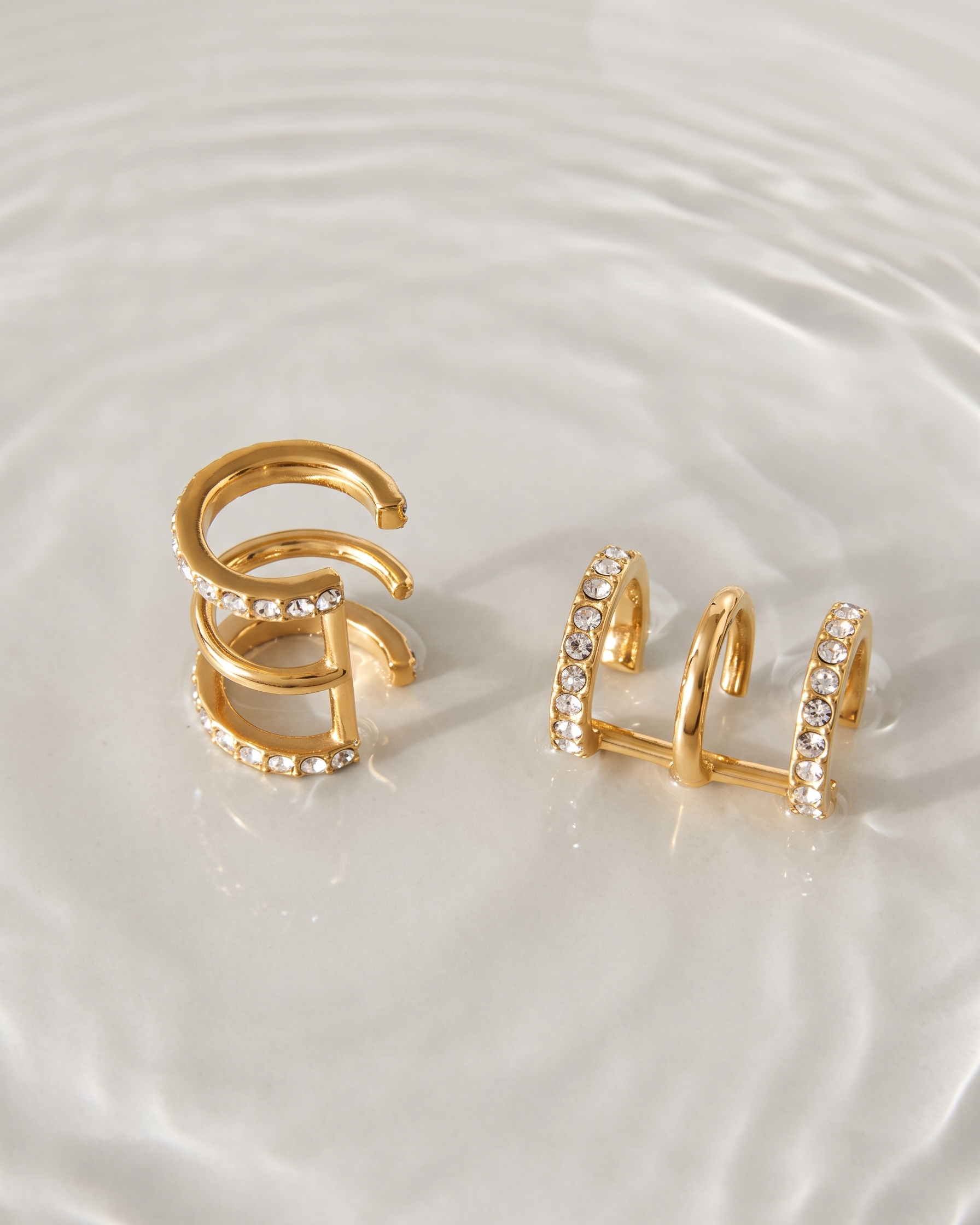 Gold hoop earrings with embedded stones on a white plate