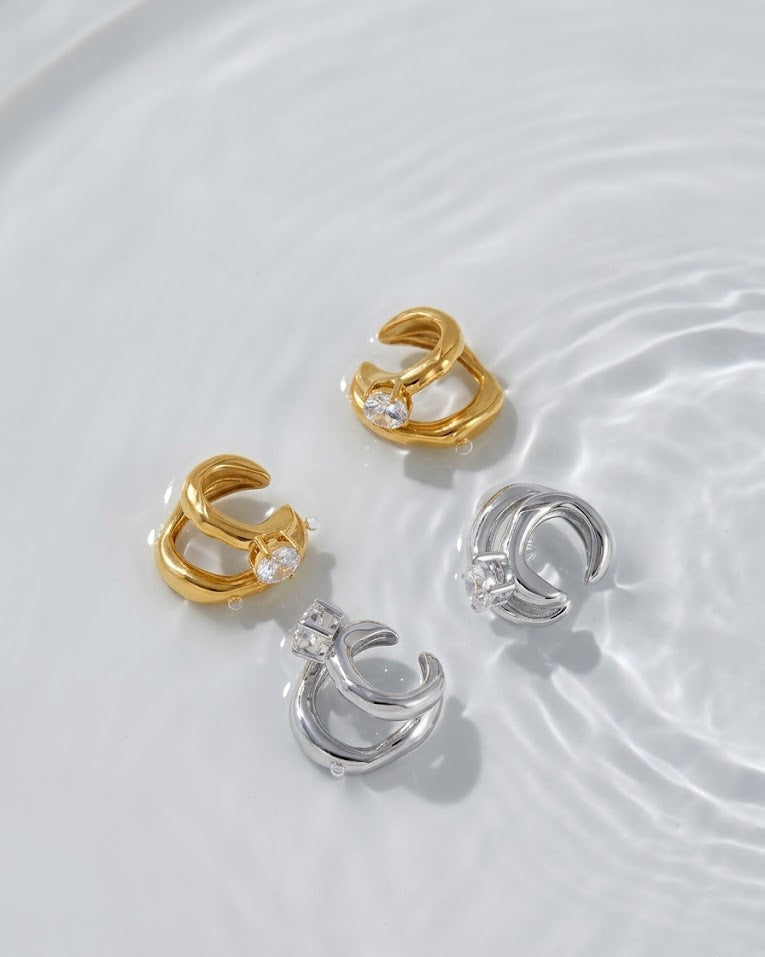 Three gold and silver earrings on a water surface