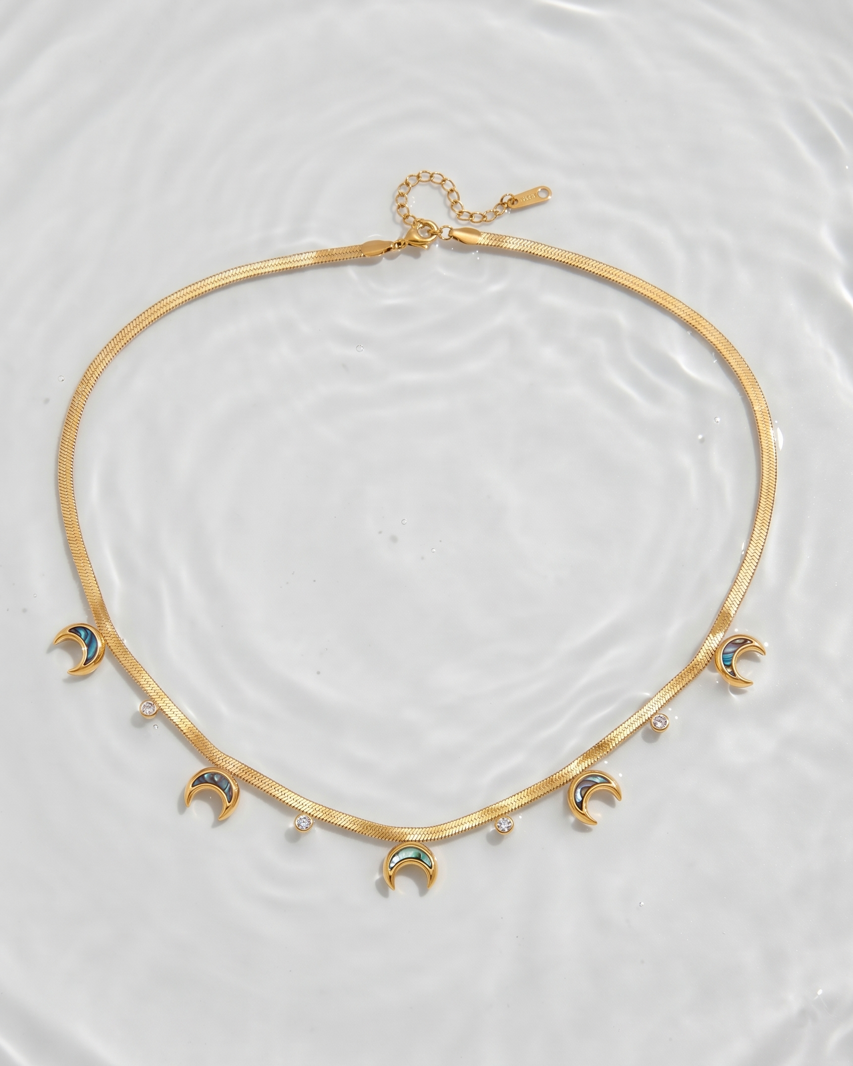 Gold necklace with moon phases on a white background