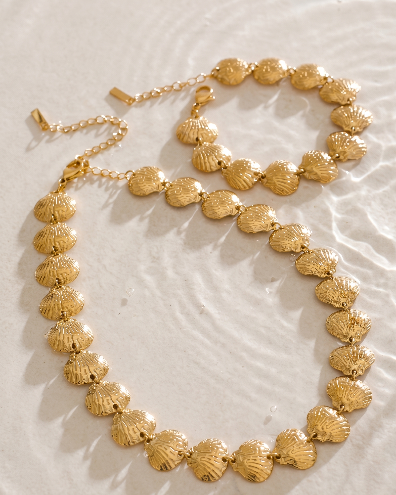 Gold necklace and bracelet set on a textured surface