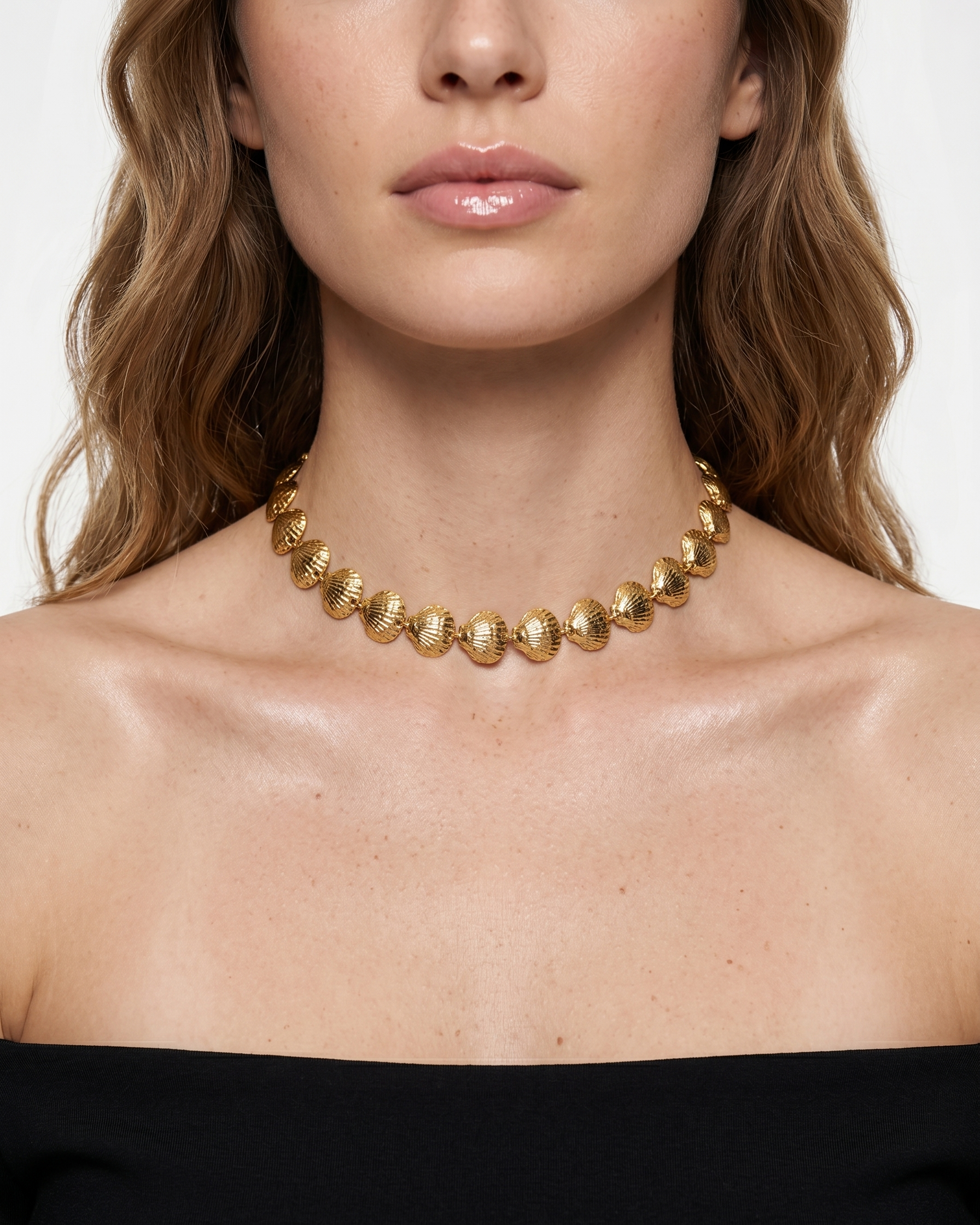 Close-up of a woman wearing a gold necklace against a white background