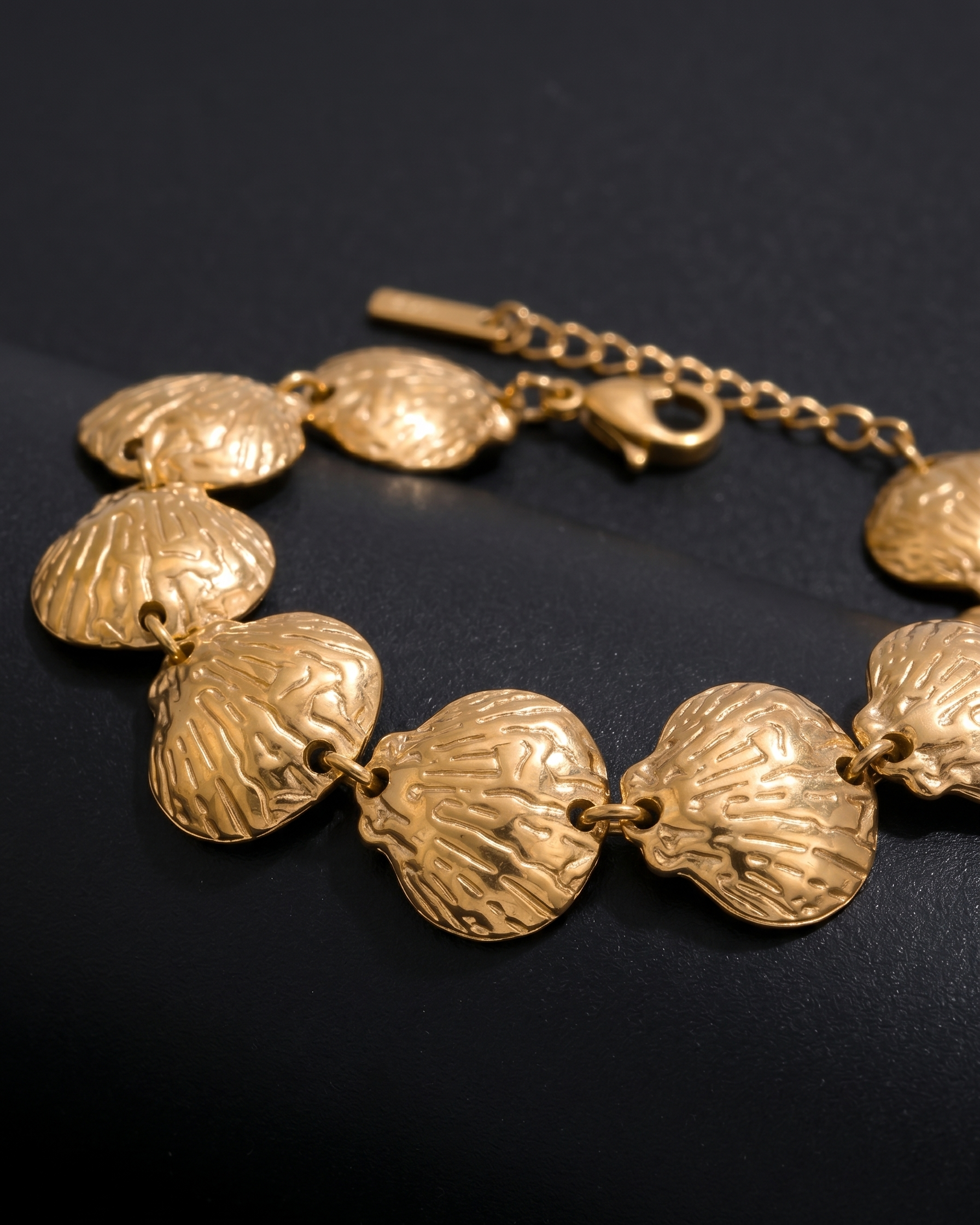 Gold bracelet with shell-like links on a dark background