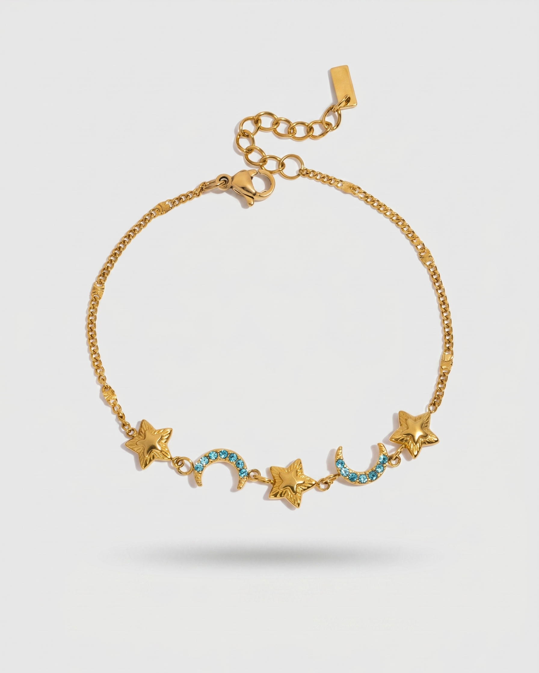 Gold bracelet with star and moon charms on a light gray background